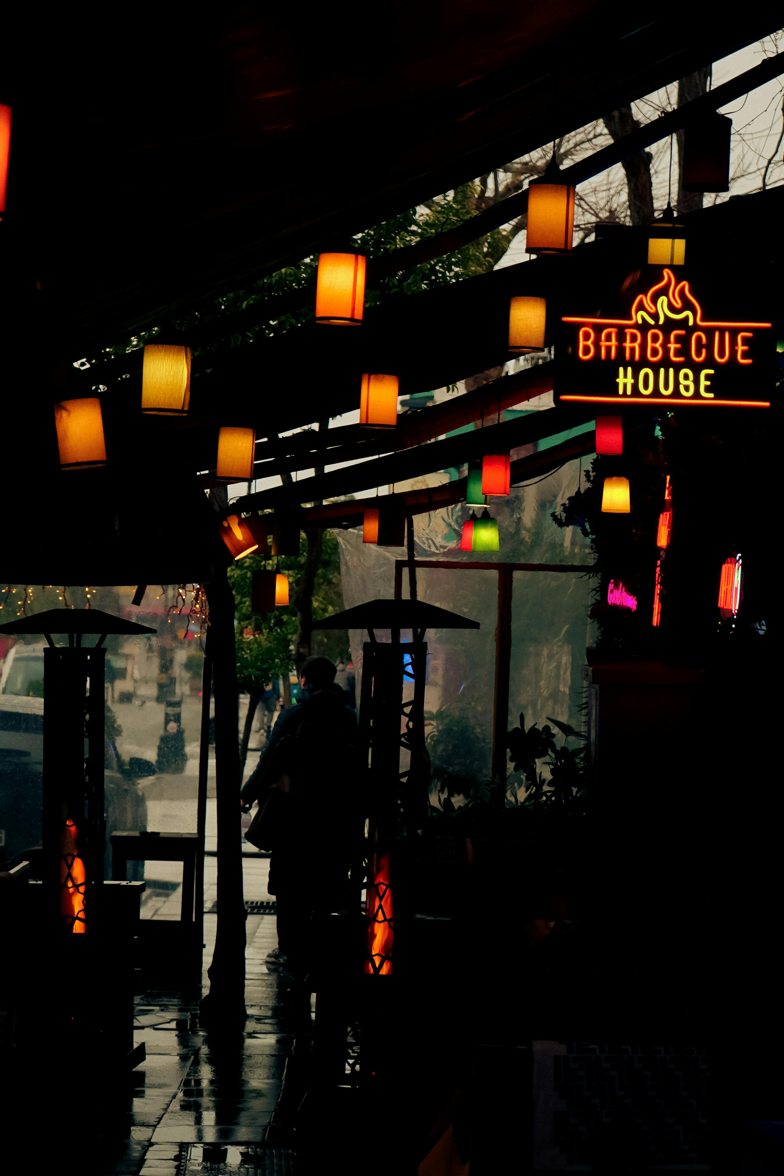 Безкоштовне Тепла атмосфера всередині барбекю-будинку з барвистими лампами під час дощової ночі. стокове фото