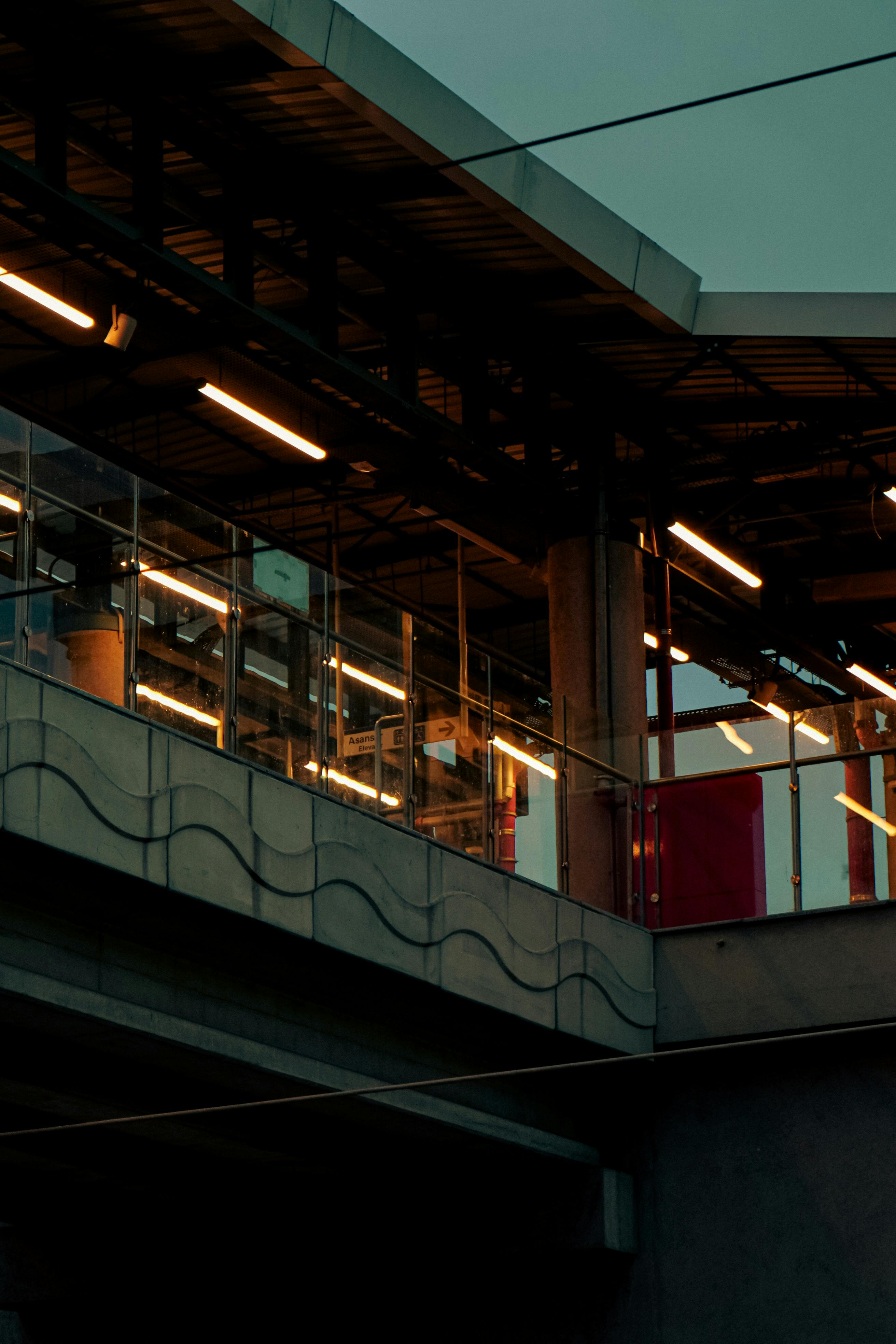 Безкоштовне Захопливий вид на сучасний міський залізничний вокзал у сутінках, що демонструє архітектурні елементи та освітлення. стокове фото