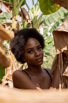 一幅美丽的女性肖像被郁郁葱葱的热带树叶环绕，沐浴在自然光中