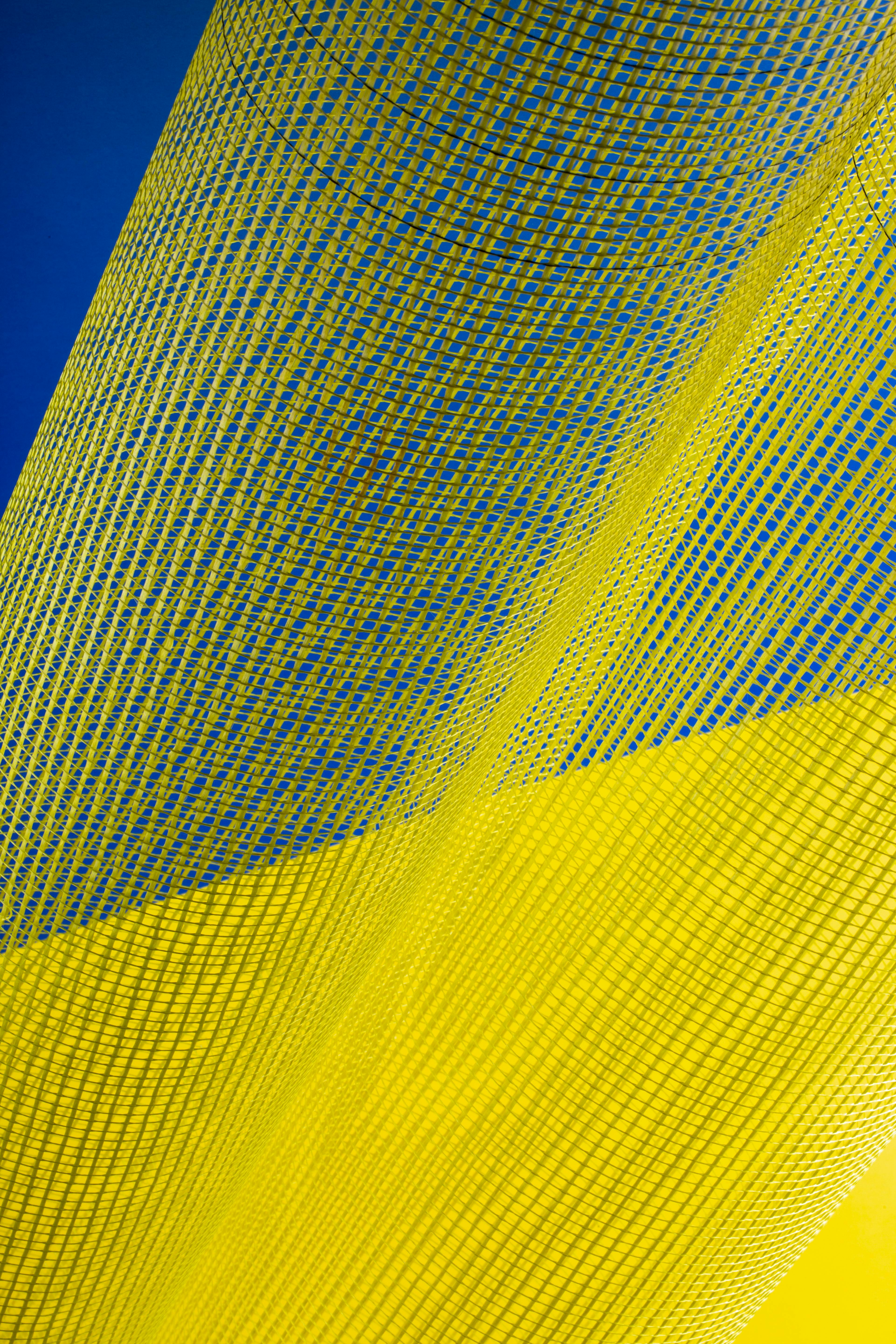 ingyenes Dinamikus absztrakt kép áramló sárga hálós anyagról kék háttér előtt. Stockfotó