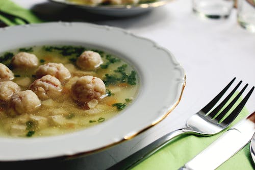 Free Close-up Photography of Soup in Round Plate Beside Stainless Steel Fork Stock Photo