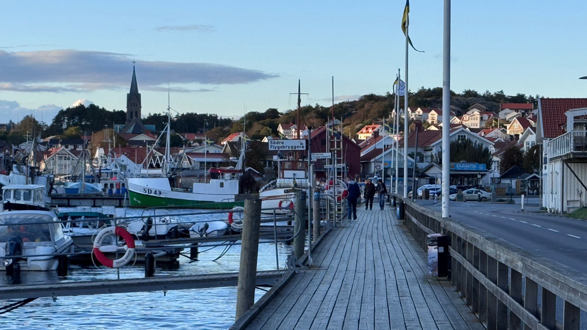 Extérieur d'une petite église en bois peinte en blanc, sur le quai d'un port, avec l'eau en arrière-plan.