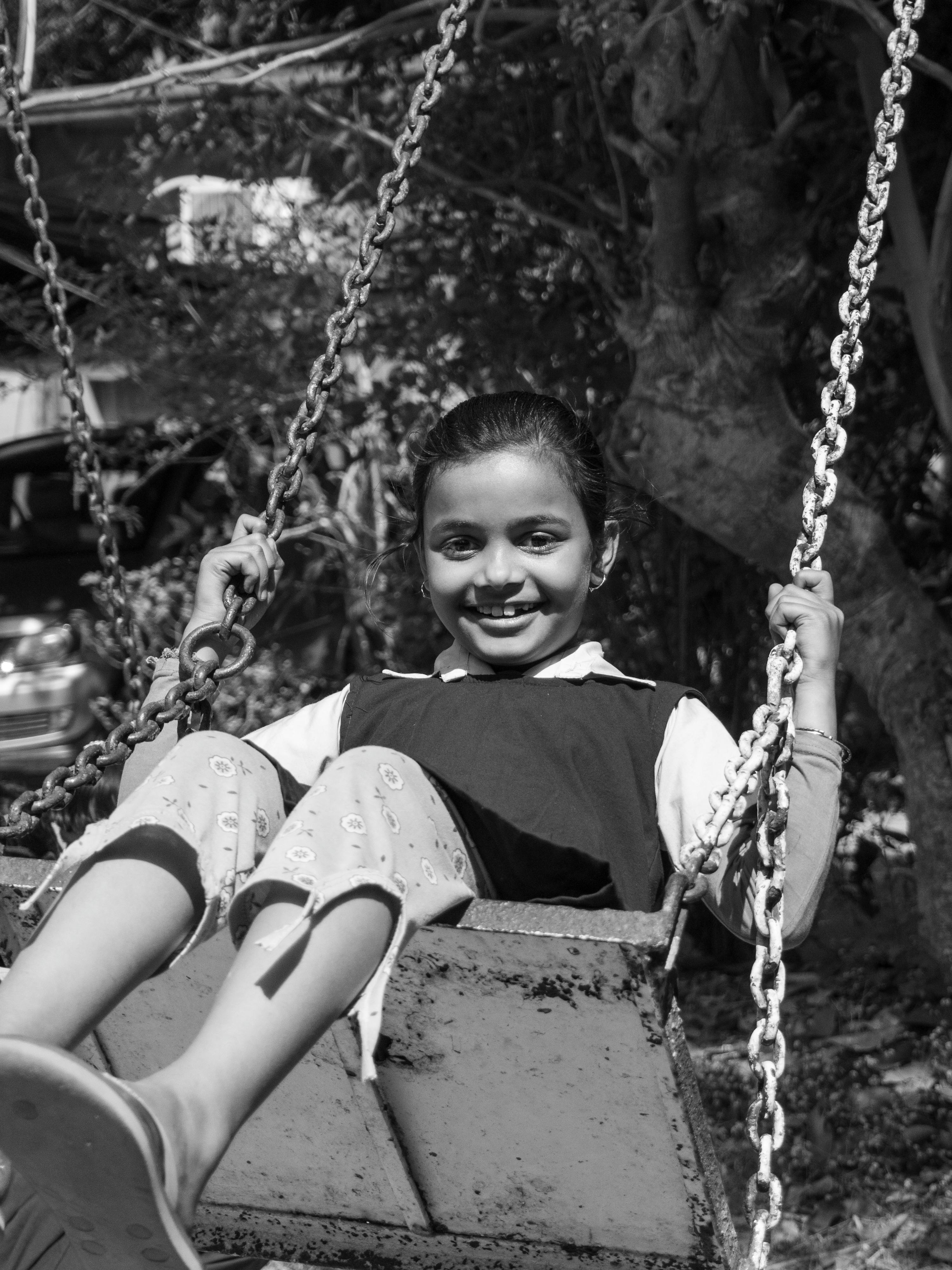 bezplatná Veselá mladá dívka si užívá houpačku venku, zachycená v klasické černobílé technologii. Základová fotografie