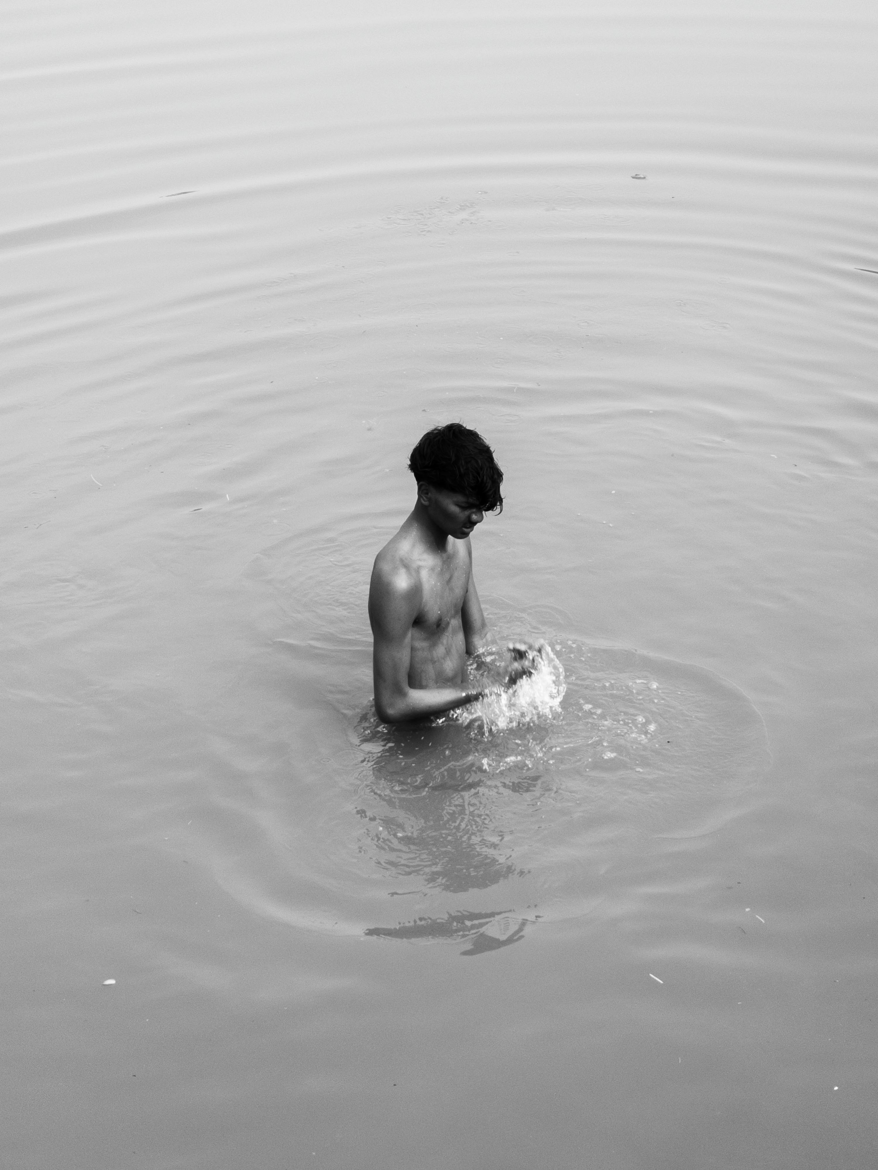 Безкоштовне Молодий чоловік урочисто стоїть на спокійній воді, створюючи навколо себе брижі. стокове фото