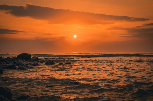 Free A breathtaking sunset over the ocean with an orange sky and gentle waves. Stock Photo