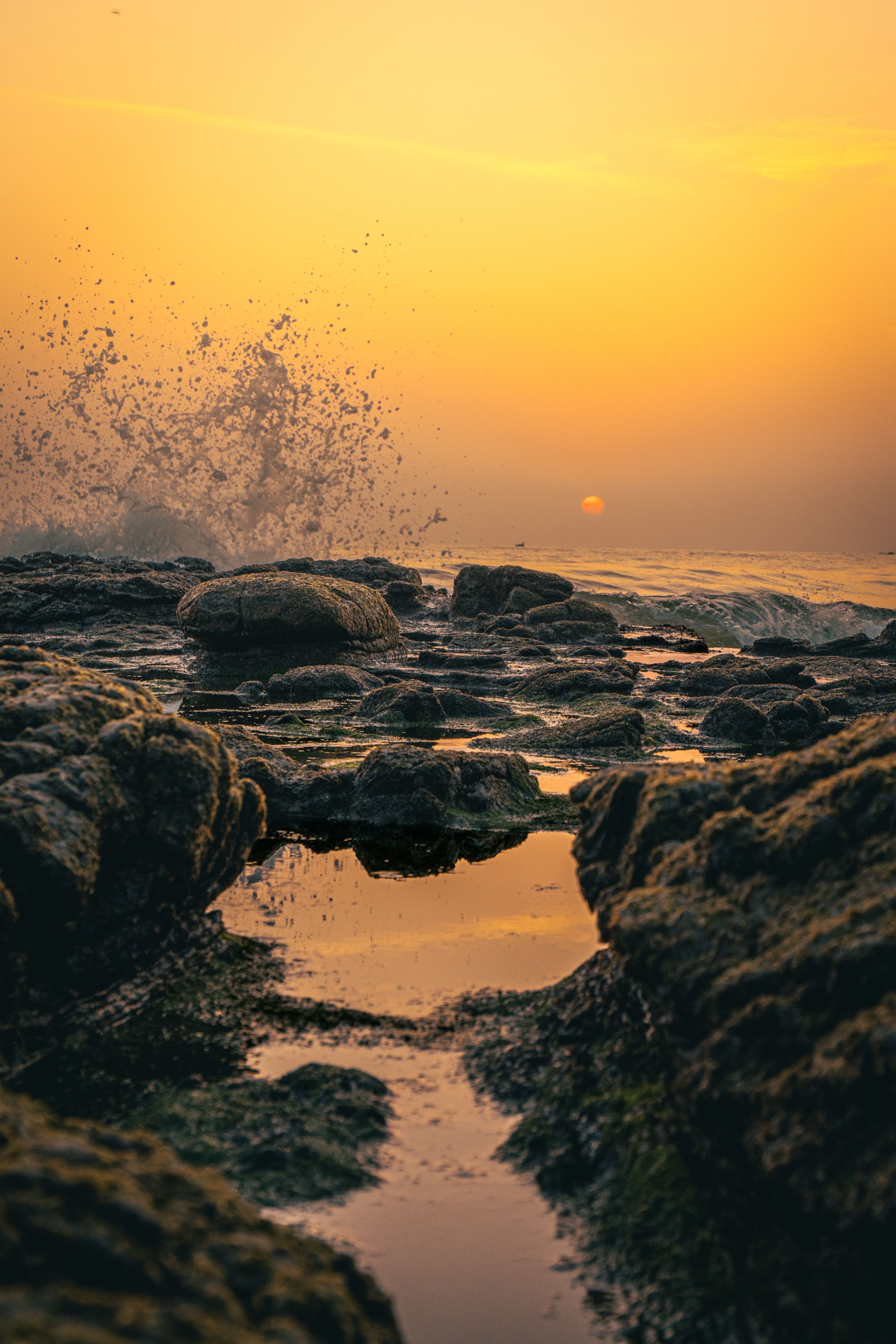 Sunset Over Rocky Shoreline with Splashing Waves · Free Stock Photo