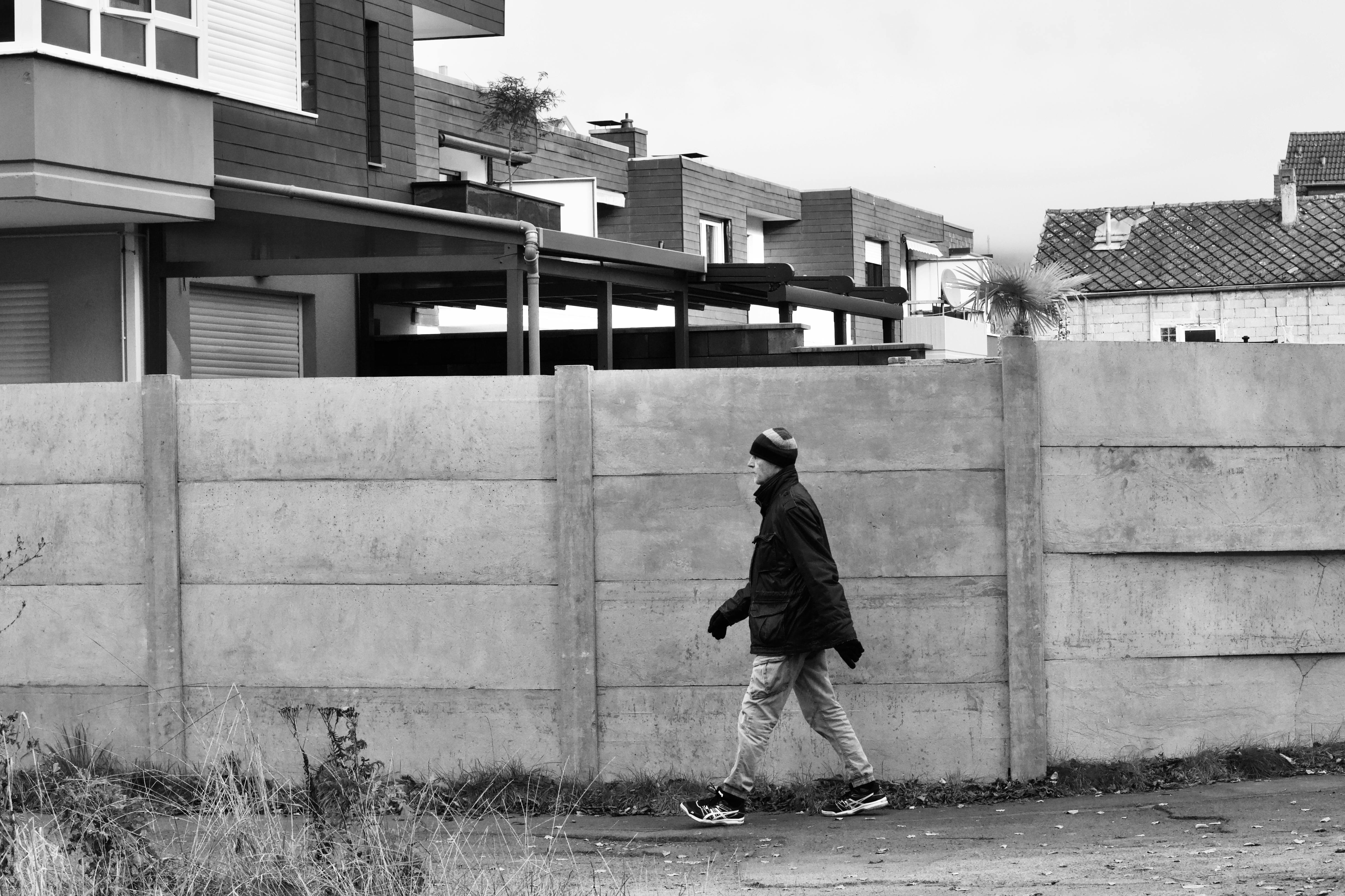 Δωρεάν Ασπρόμαυρη φωτογραφία ενός ατόμου που περπατάει δίπλα σε σύγχρονα κτίρια. Φωτογραφία από στοκ φωτογραφιών