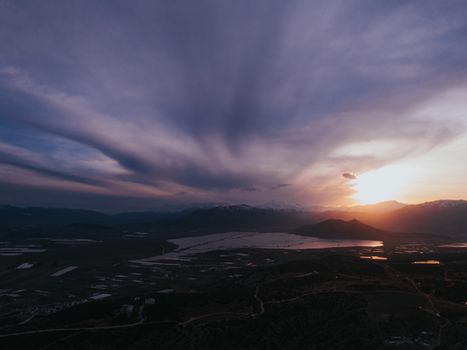 A breathtaking aerial view of a stunning sunset over a tranquil lake with dramatic cloud formations.