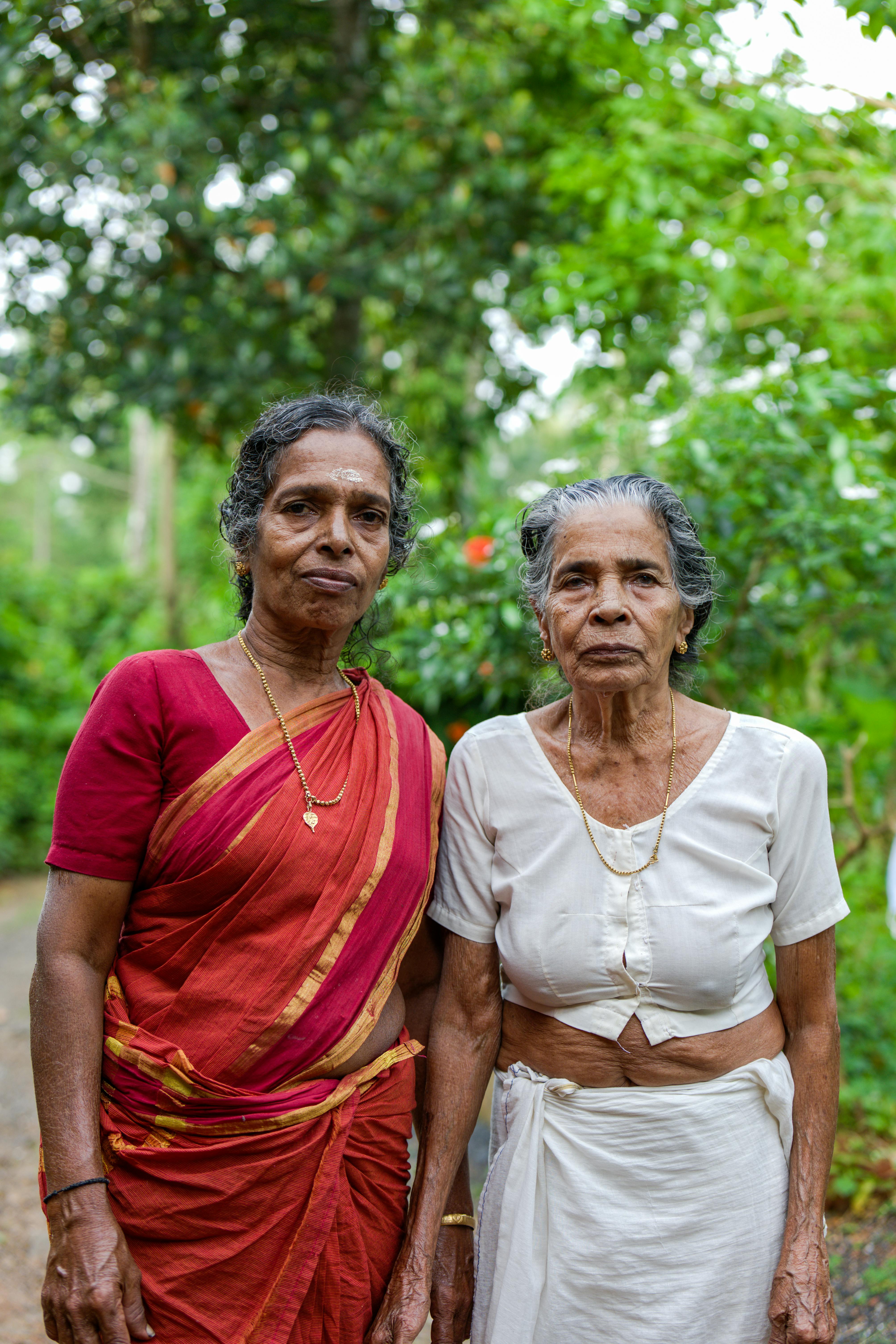Gratuit Deux femmes âgées vêtues de vêtements traditionnels d'Asie du Sud se tiennent à l'extérieur, au milieu de la verdure. Photos