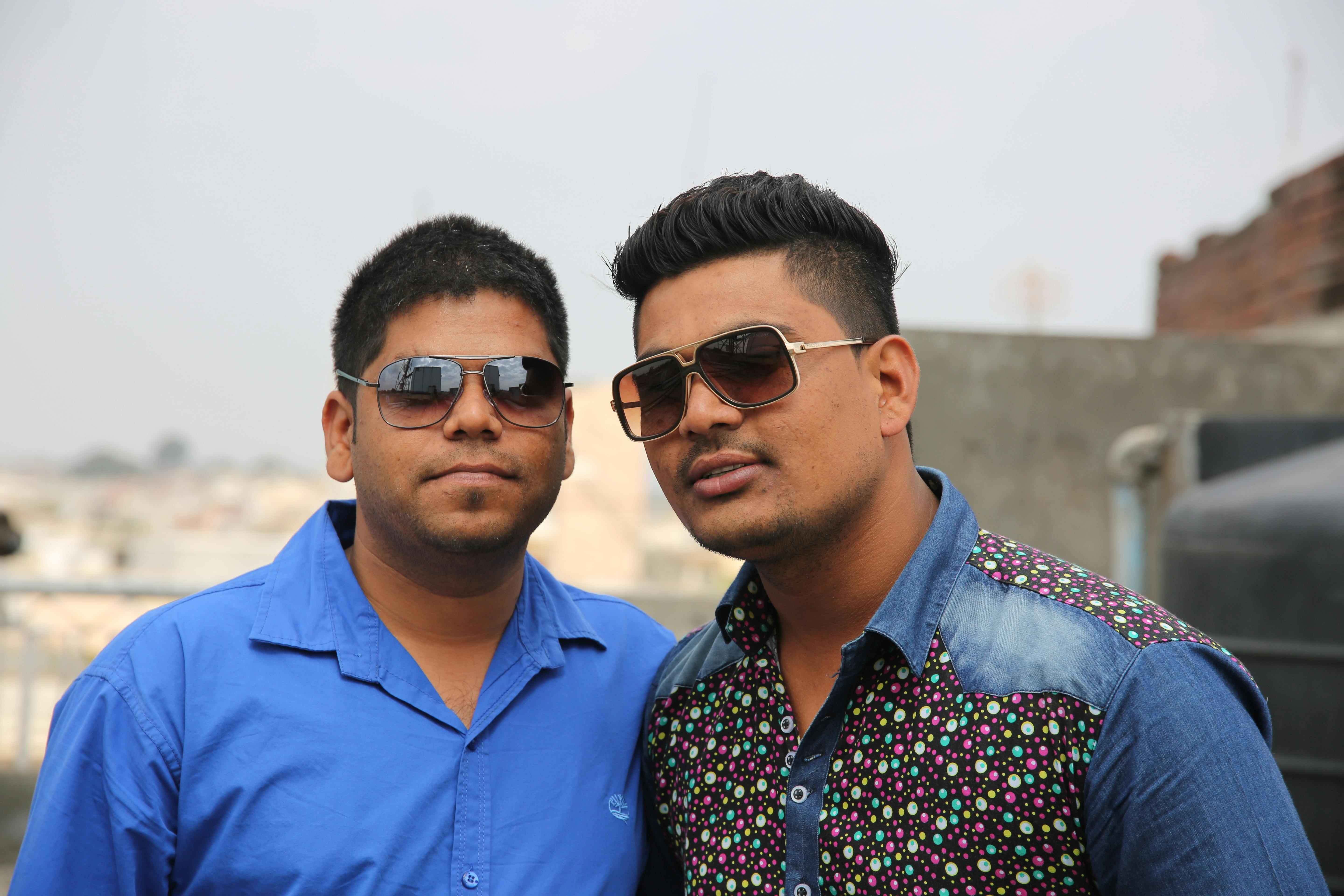 bezplatná Dva mladí muži se slunečními brýlemi sebevědomě pózují venku. Ležérní a stylová atmosféra. Základová fotografie