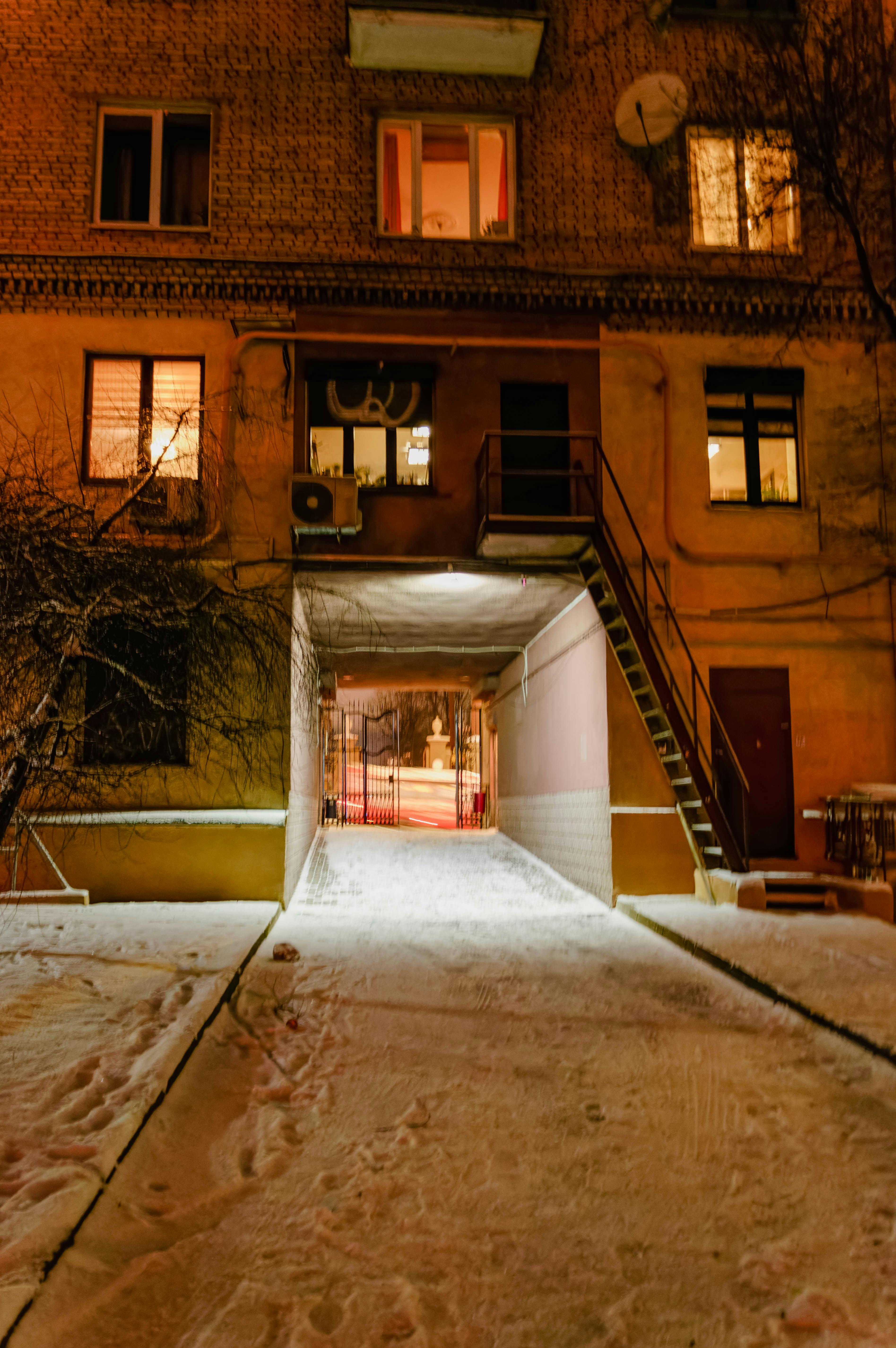 Free Snow-covered alley at night in Minsk, showcasing urban architecture with warm lights. Stock Photo