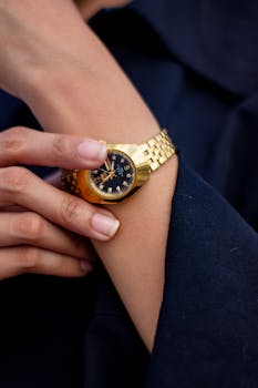 手腕上，时尚金色手表的特写镜头正在调整，凸显计时的优雅