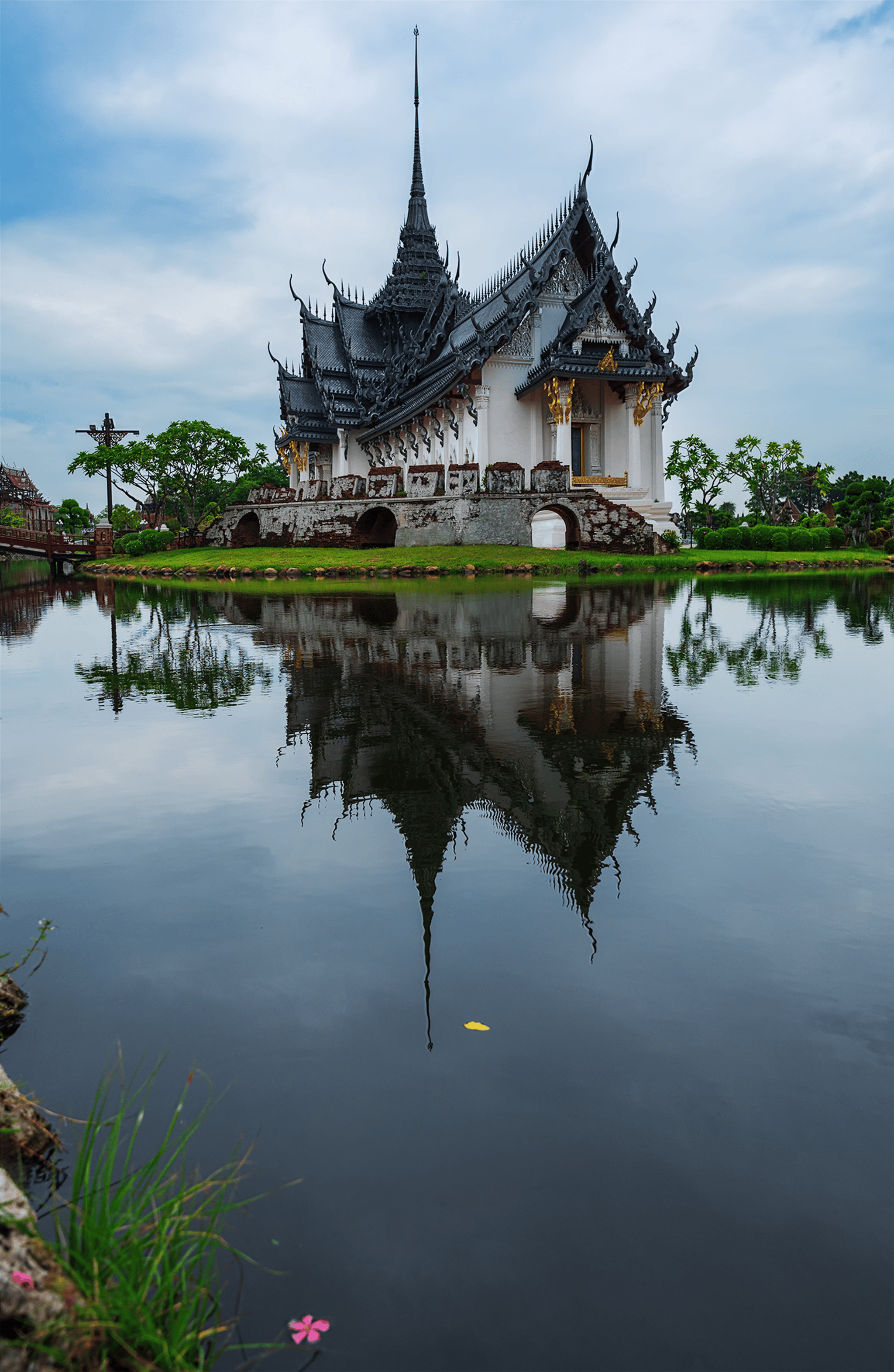Gratis Smukt thailandsk tempel med spejling i en fredfyldt sø under en overskyet himmel. Lagerfoto