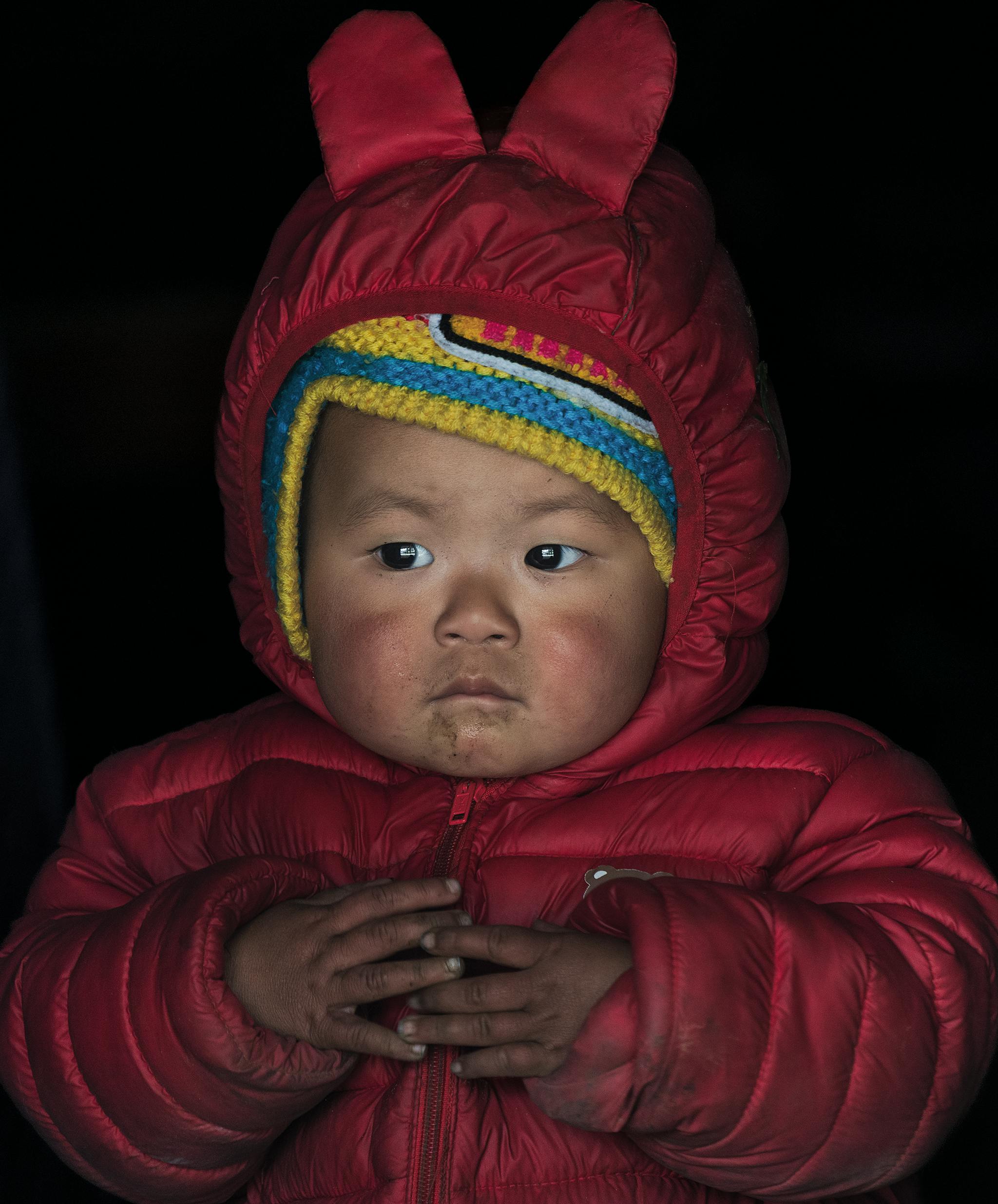 免费 可爱的孩子穿着温暖的冬装，红色外套，鲜艳的毛线帽，在室内。 素材图片