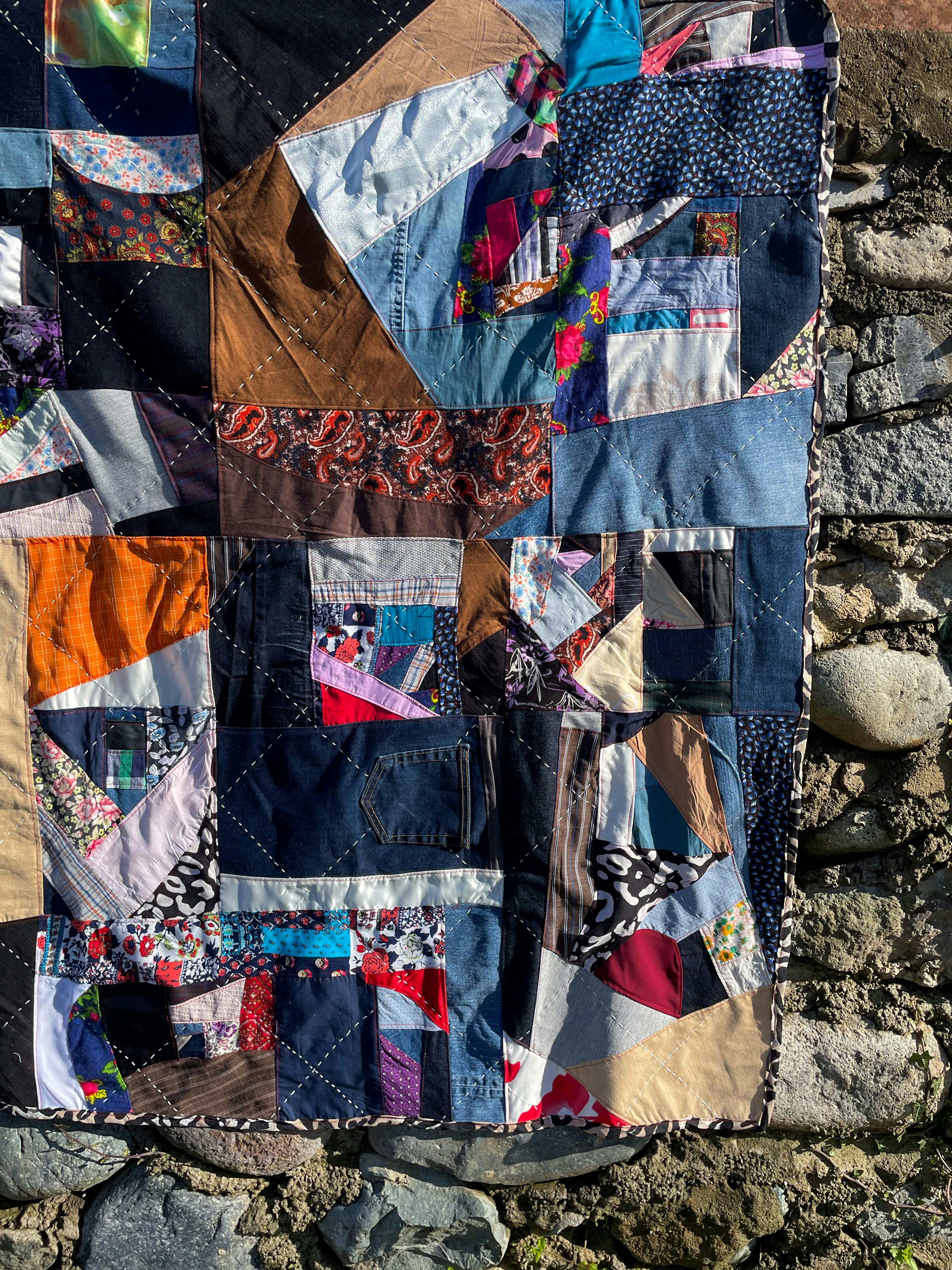 Gratis Colcha de retazos con estampados vibrantes sobre un fondo de pared de piedra al aire libre. Foto de stock