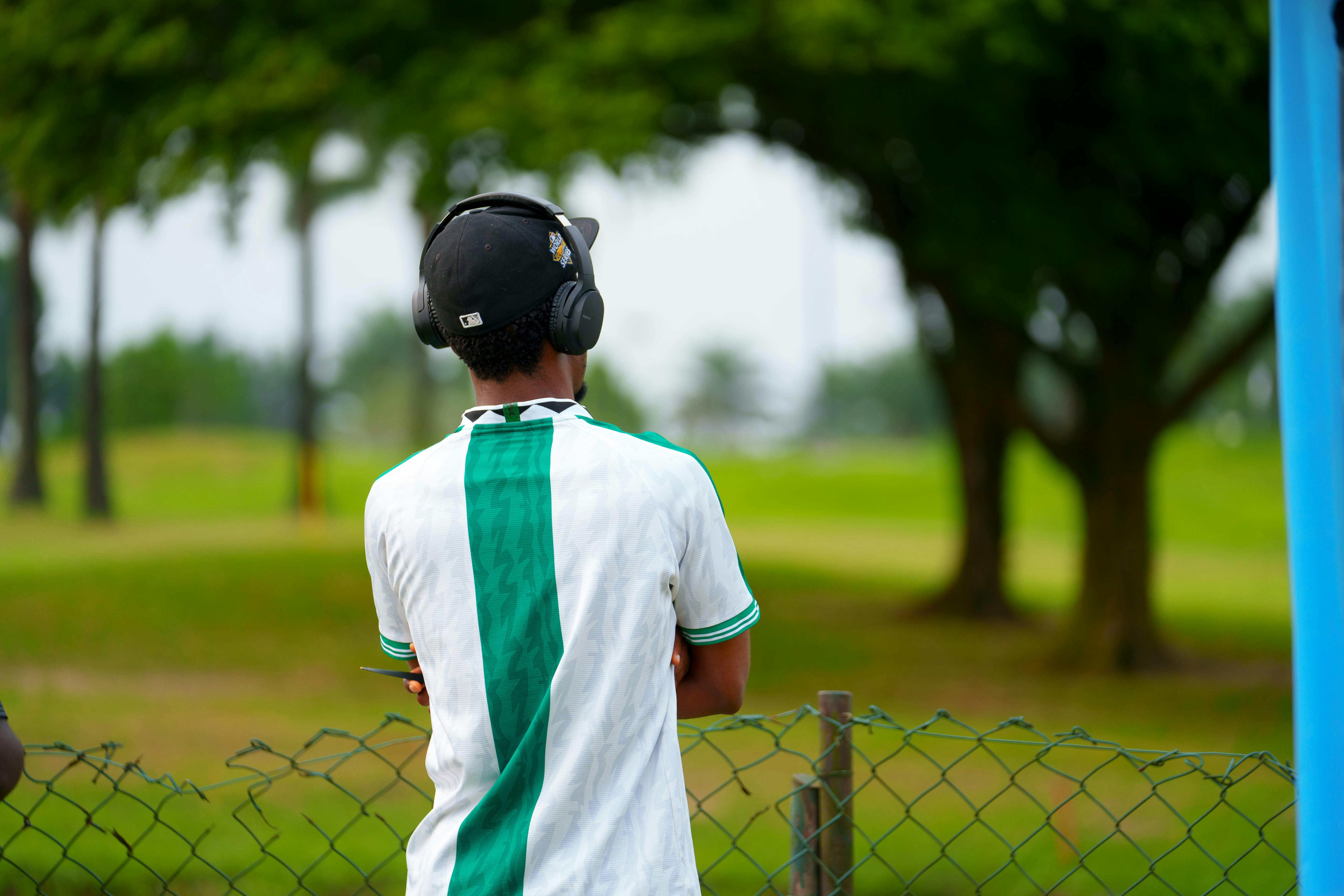Bezpłatne Młody mężczyzna ze słuchawkami słucha muzyki w spokojnym otoczeniu na świeżym powietrzu. Zdjęcie z galerii