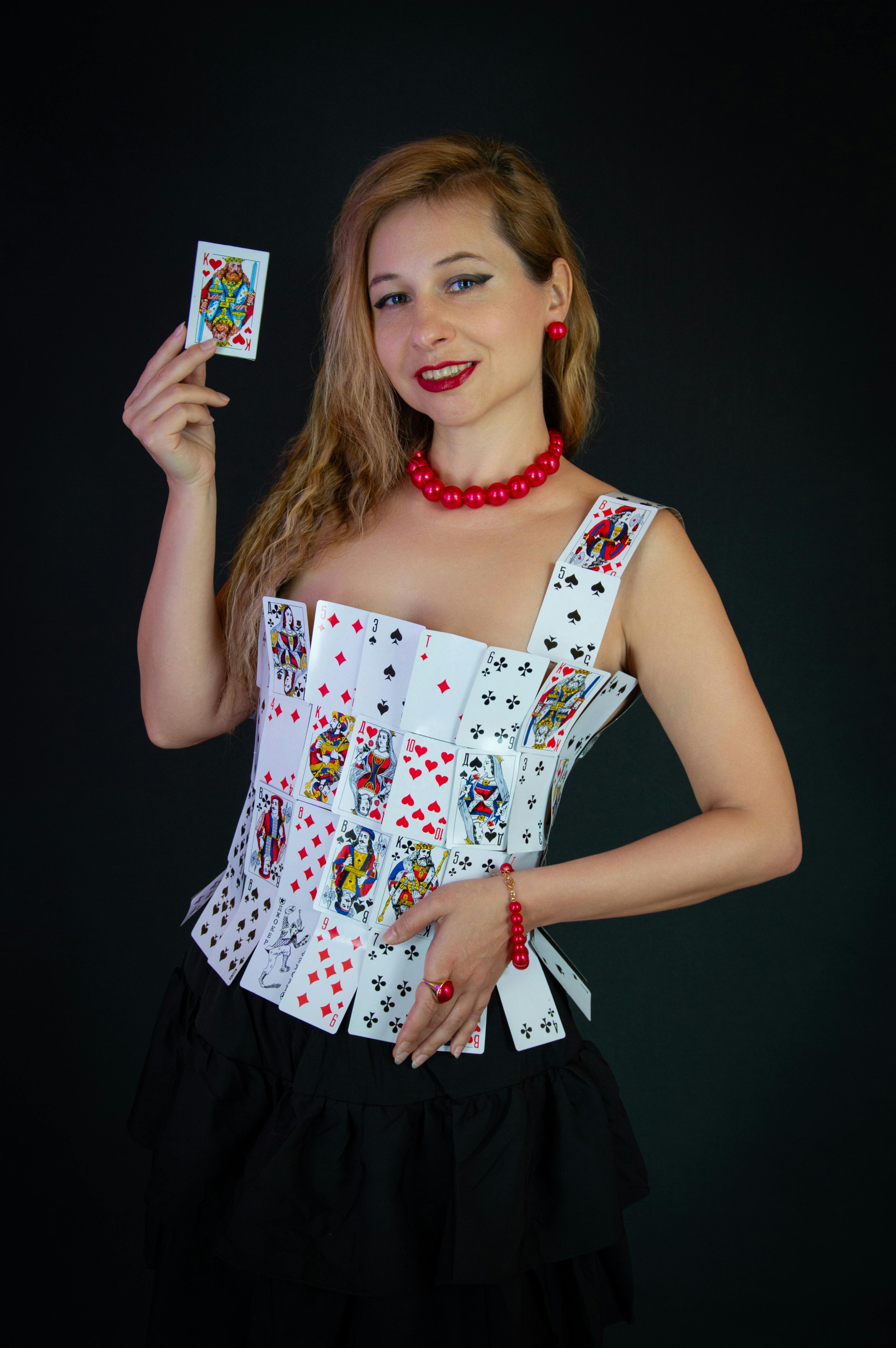 Gratis Una mujer vestida con un peculiar atuendo inspirado en las cartas de póker sostiene un comodín con una sonrisa segura. Foto de stock