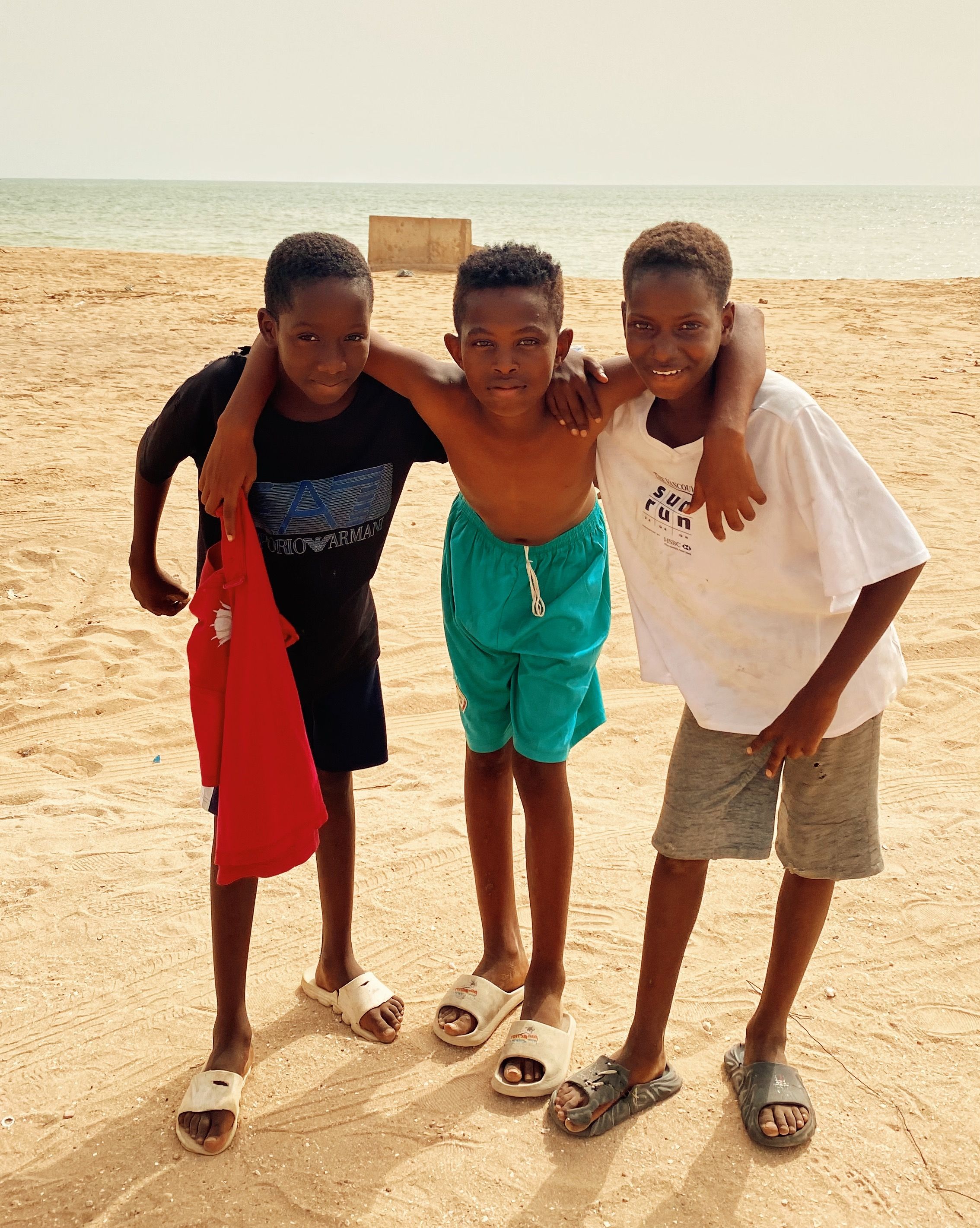 A joyful group of young boys enjoying a sunny day at the beach in Saly, Senegal.