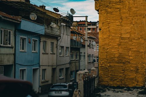 Free A narrow urban alleyway with colorful buildings and satellite dishes under a clear sky. Stock Photo