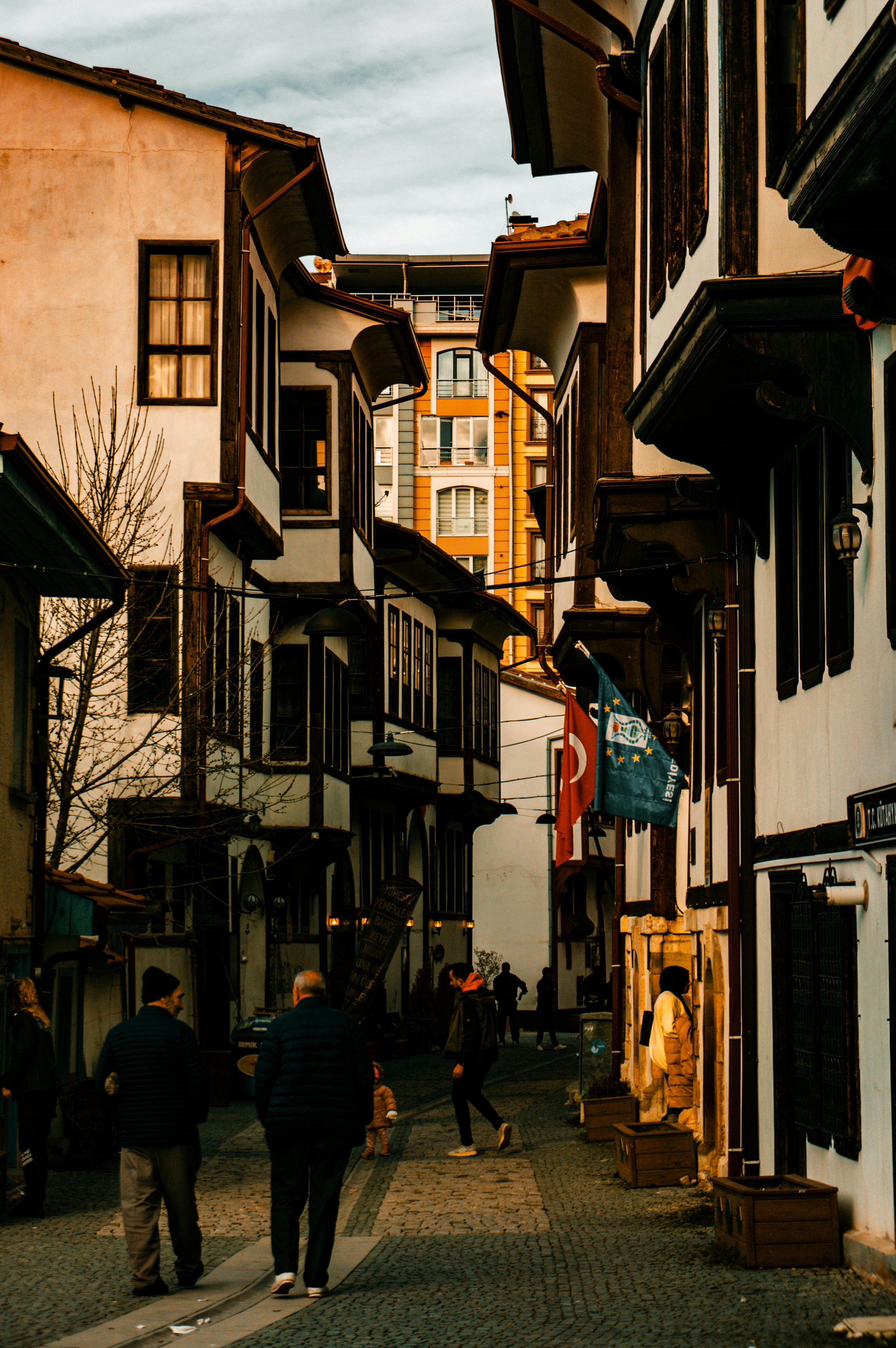 Gratis Una escena callejera histórica de estilo otomano en Turquía, con gente caminando bajo una luz cálida. Foto de stock