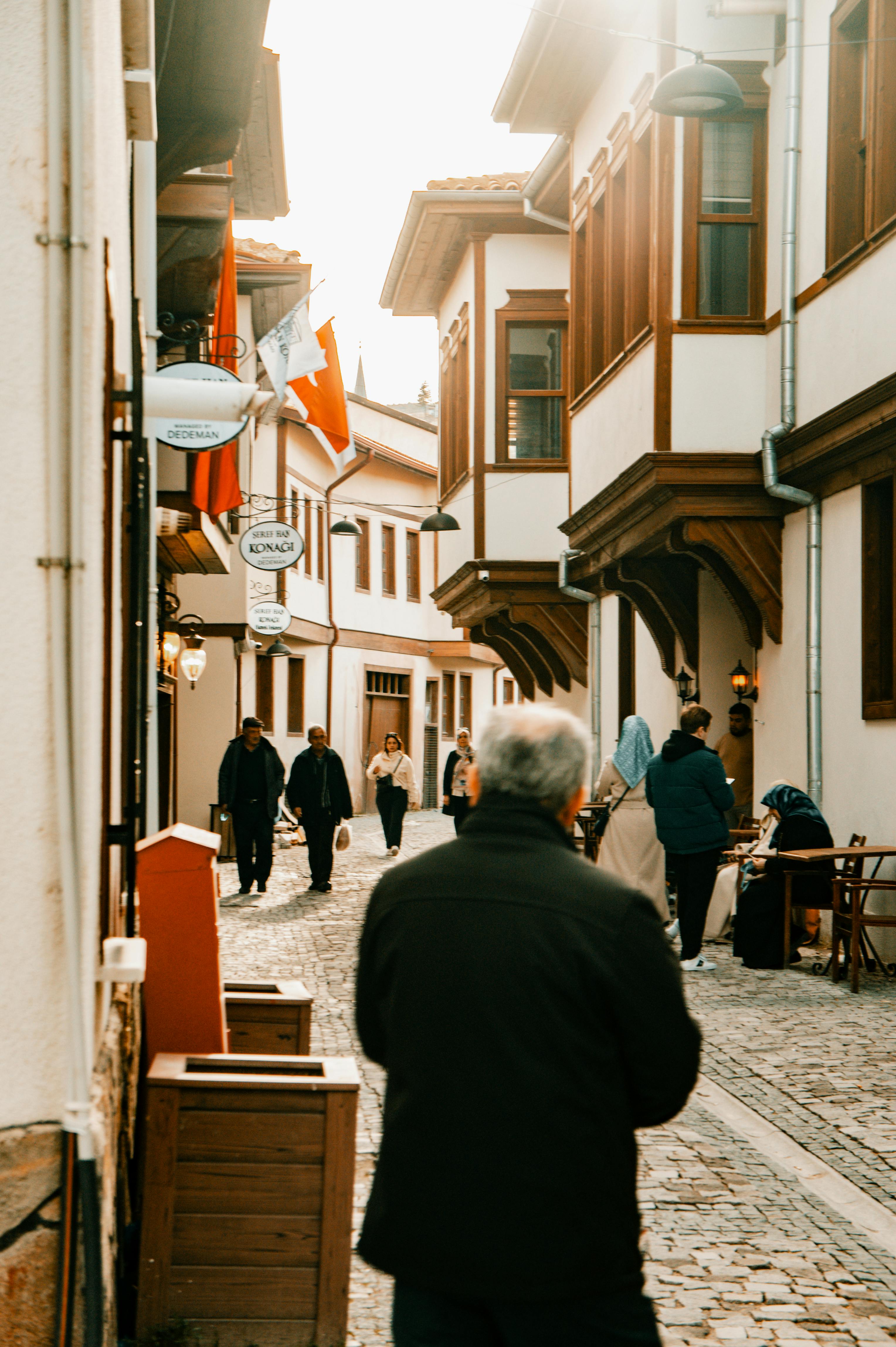 Free Cobblestone street in old town with people walking under soft sunlight. Stock Photo