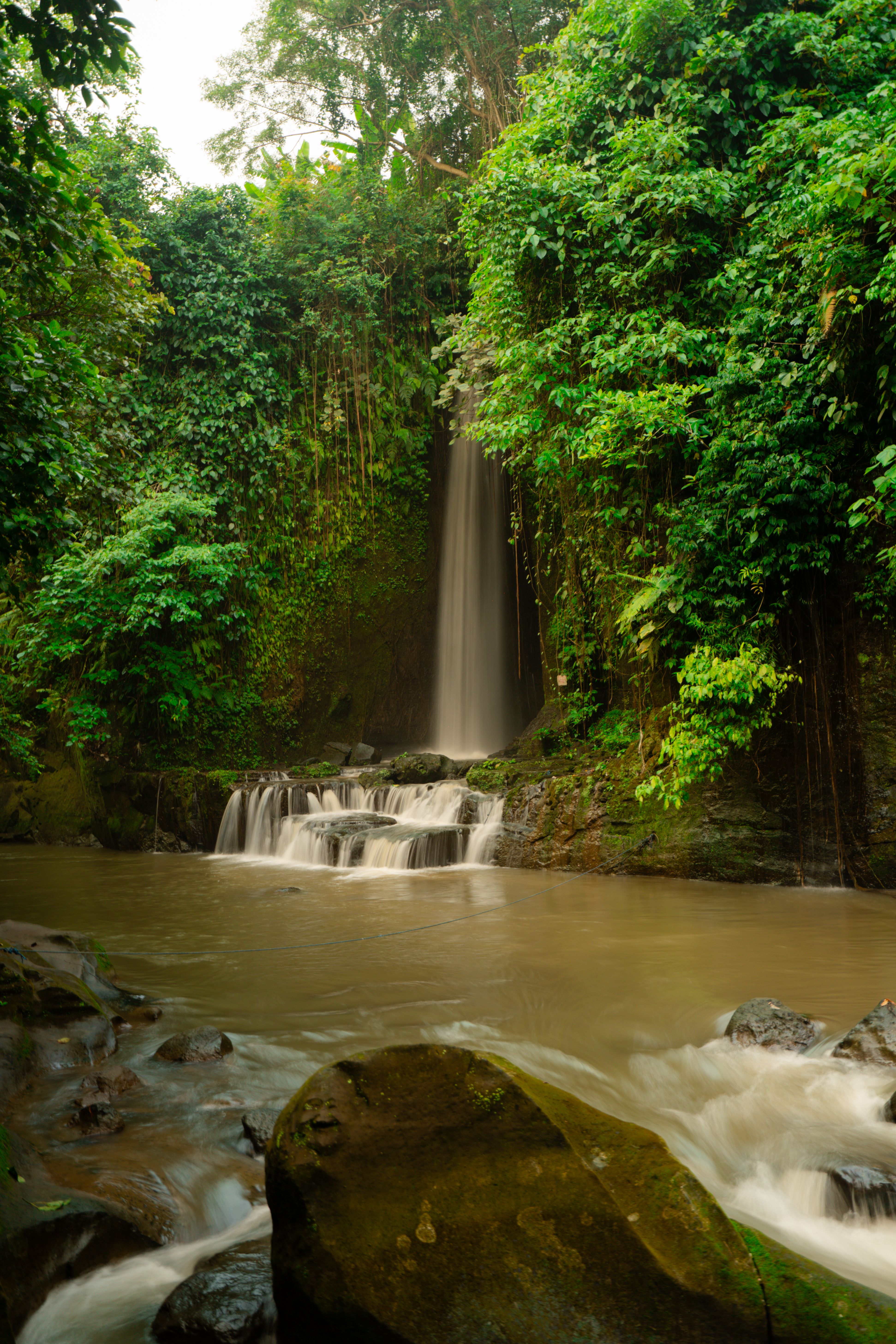 Tegenungan waterfall running at full flow through green jungle near Ubud, Bali in April
