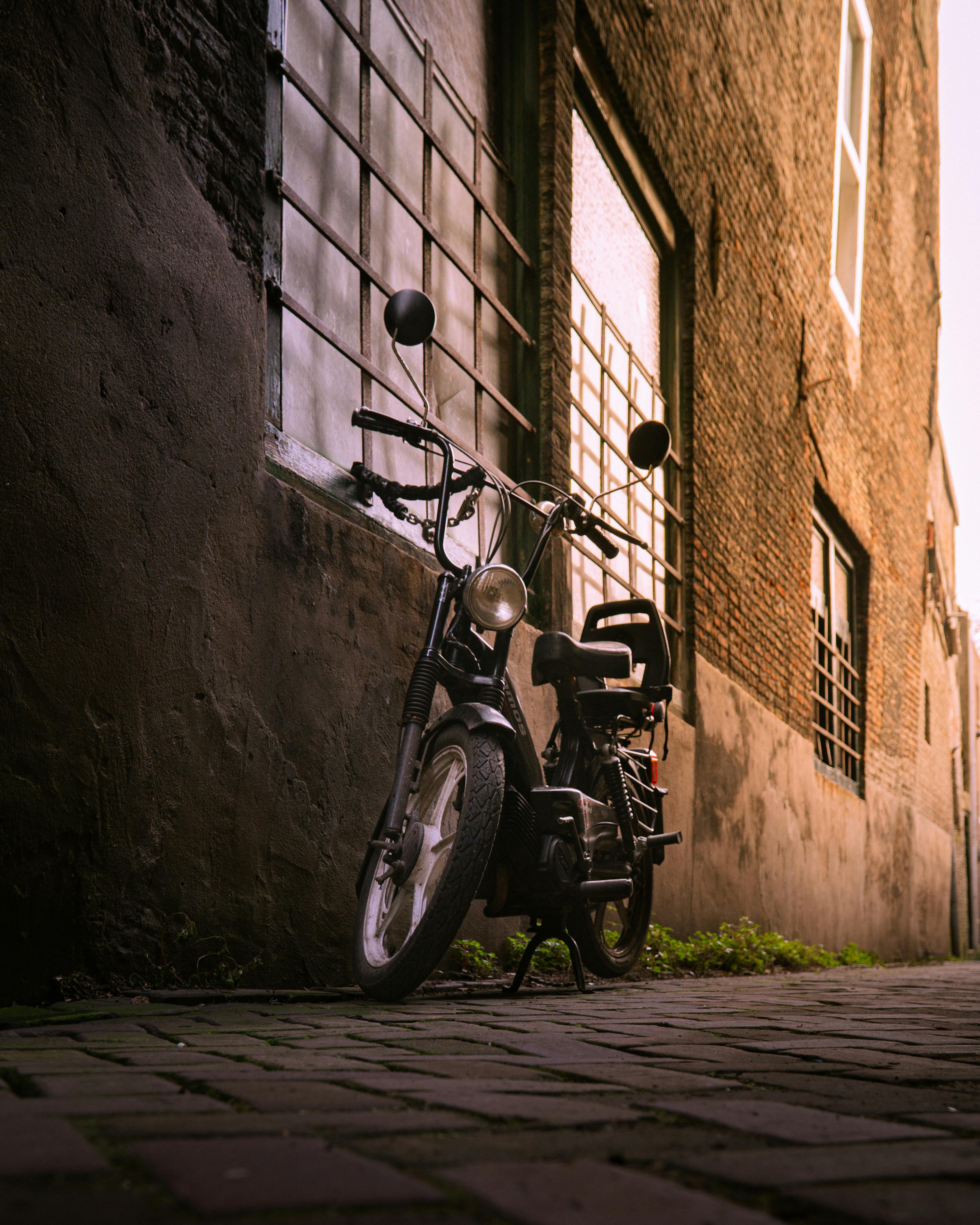 Kostenlos Ein klassisches Motorrad, geparkt in einer engen Gasse in Dordrecht, fängt den urbanen Charme perfekt ein. Stock-Foto