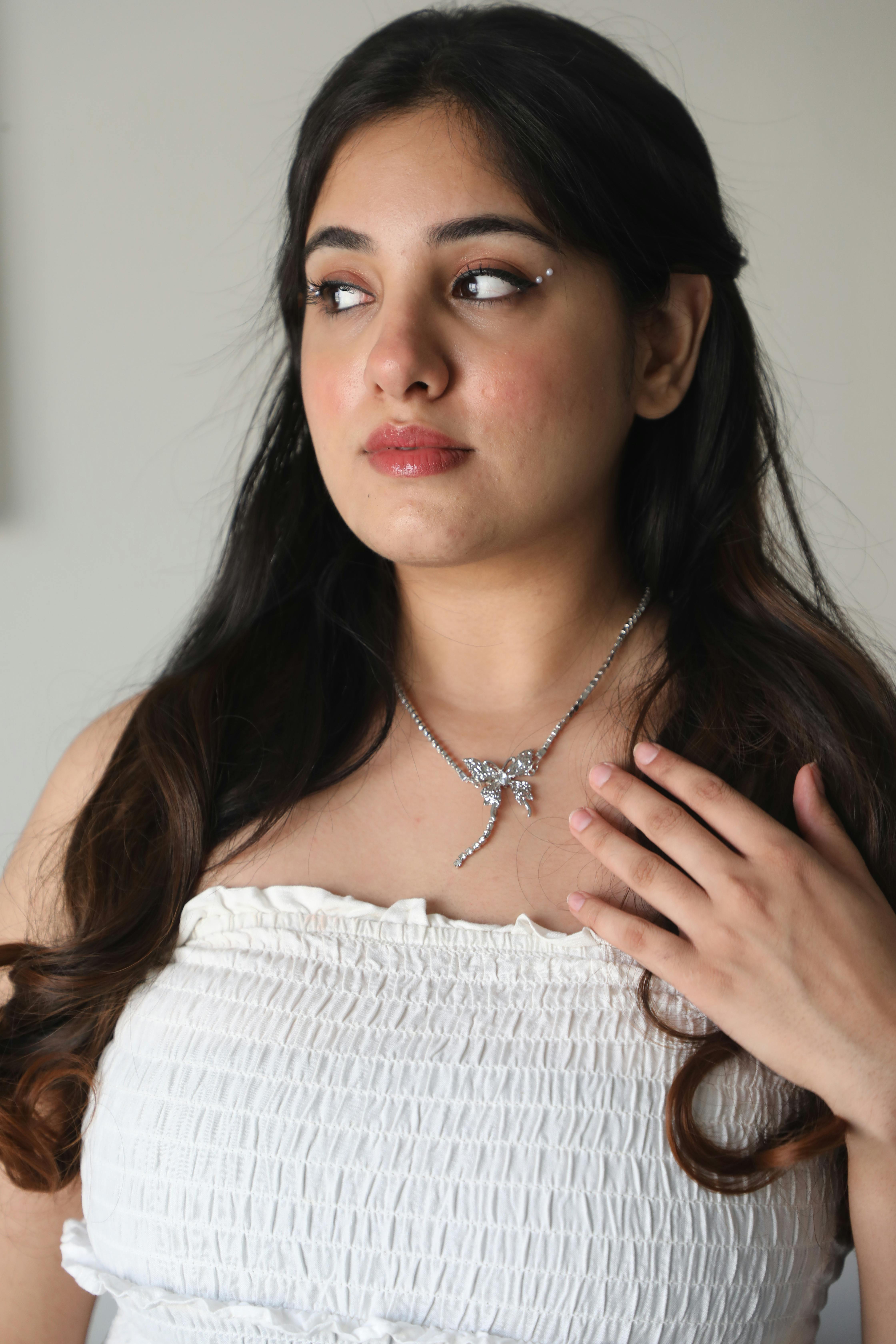 Gratis Una donna in abito bianco adornata con gioielli scintillanti. Ritratto elegante. Foto a disposizione