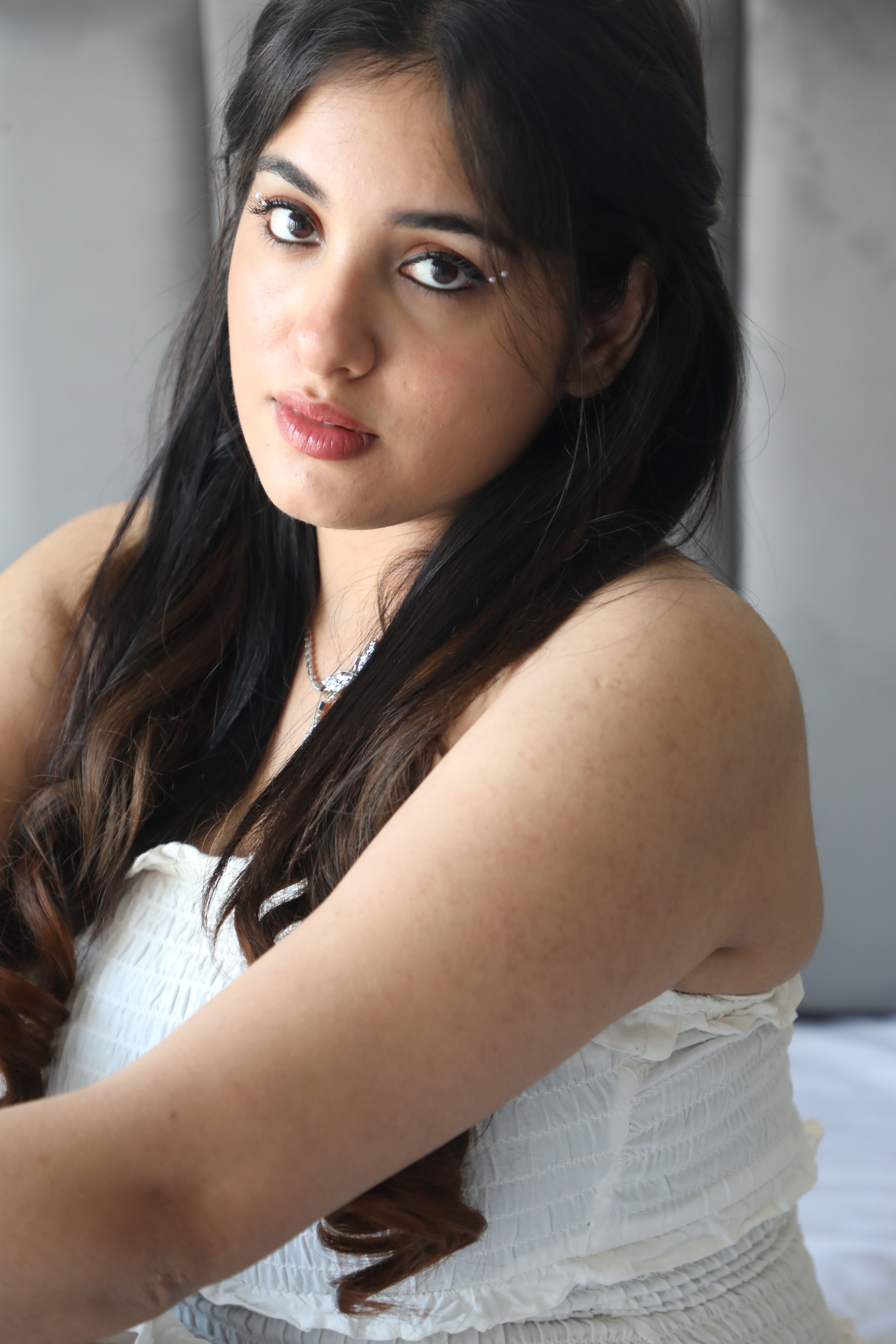 Elegant portrait of a woman with long hair in a white dress, indoors.