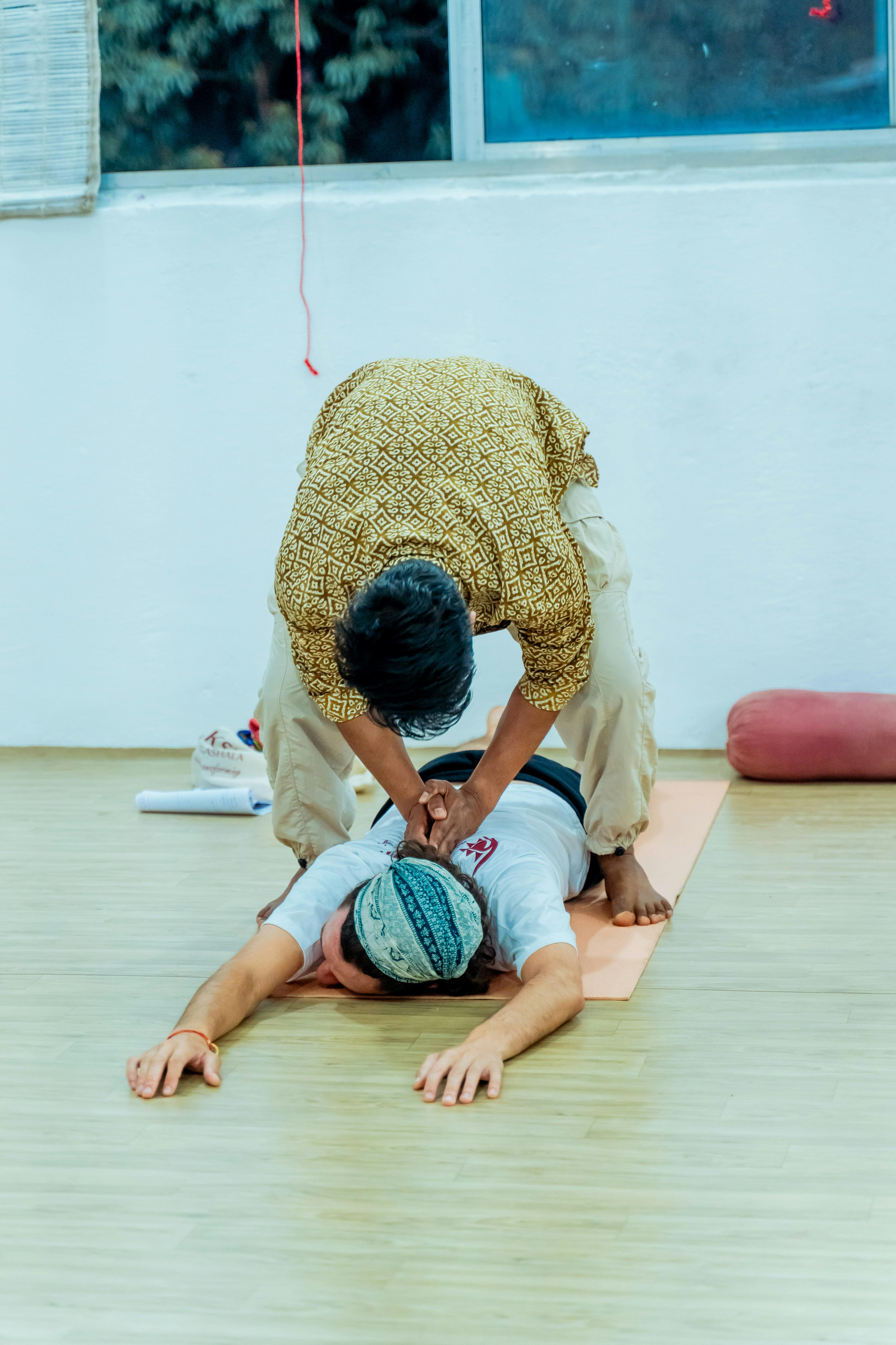 Gratis Una instructora de yoga ayuda a una alumna con sus estiramientos en un tranquilo estudio interior. Foto de stock