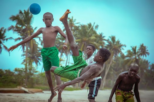 Group of boys enjoying a soccer game on a sandy beach in Ghana, capturing youthful energy and outdoor fun.