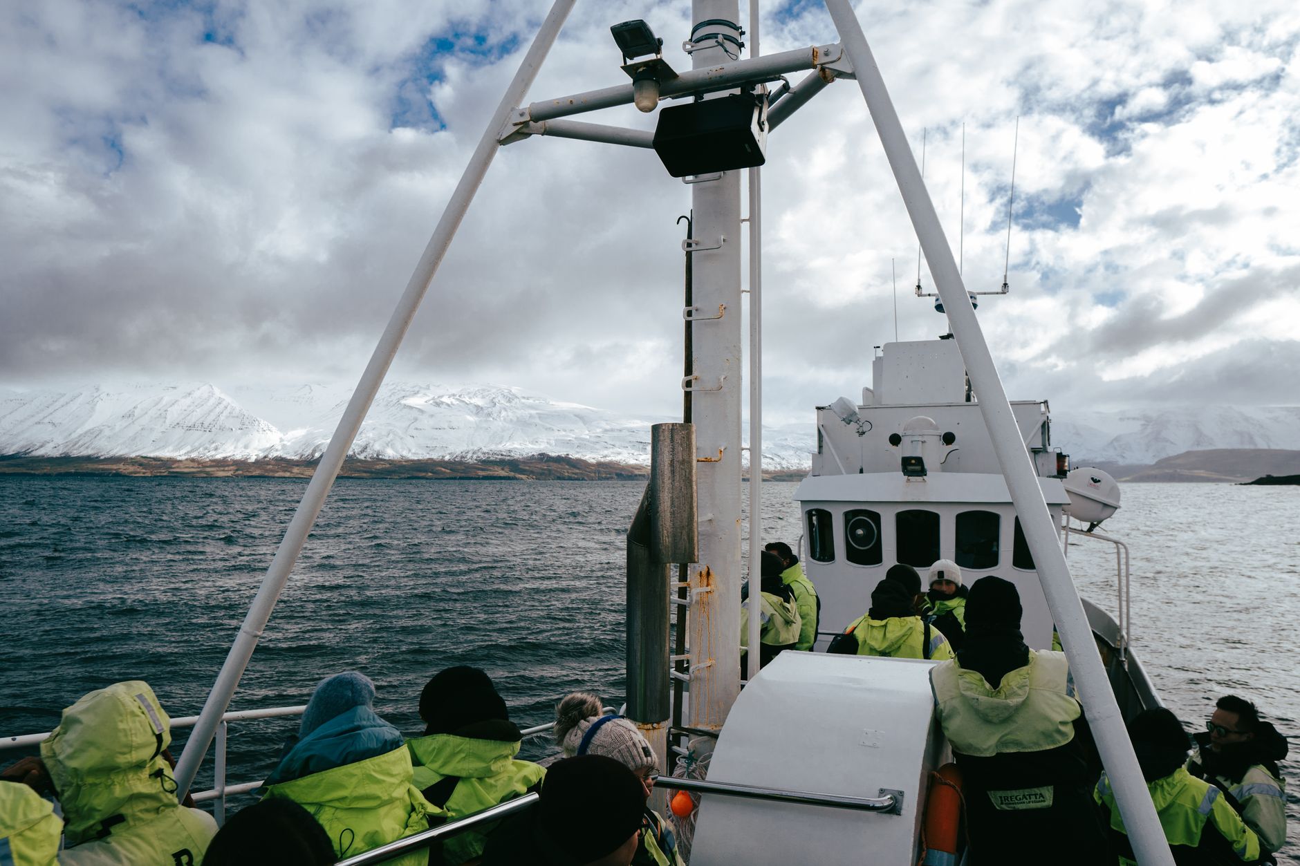A scenic whale watching tour in Árskógssandur, Iceland showcasing fjords and snowy mountains.