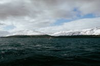 Sailboat Navigating Snowy Icelandic Fjord