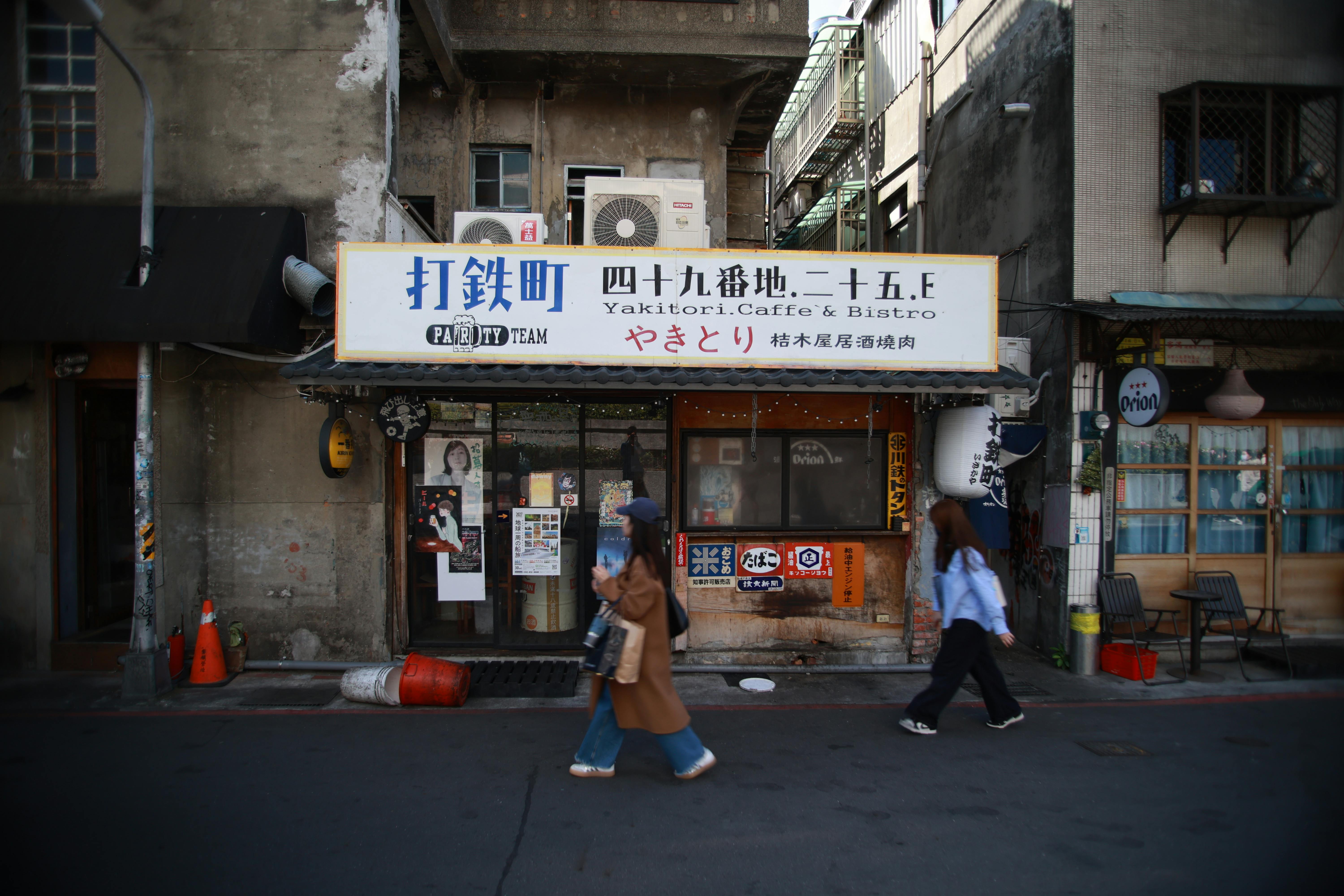 Zadarmo Dve ženy prechádzajú okolo kaviarne a bistra Yakitori na mestskej ulici. Zachytáva podstatu pouličného života. Fotka z fotobanky