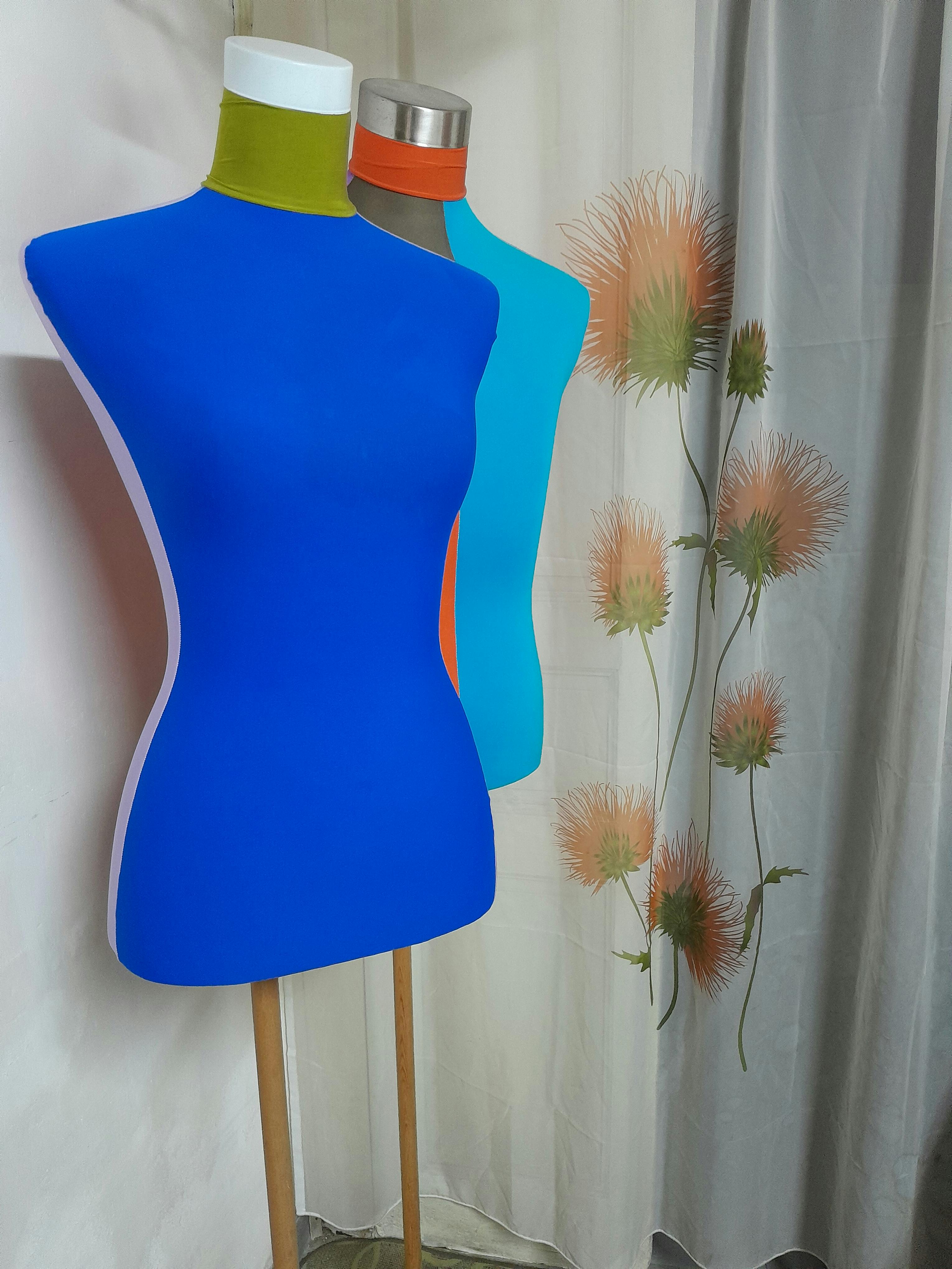 grátis Manequins em tons vibrantes de azul e verde-água em um estúdio de moda com uma cortina floral ao fundo. Foto profissional