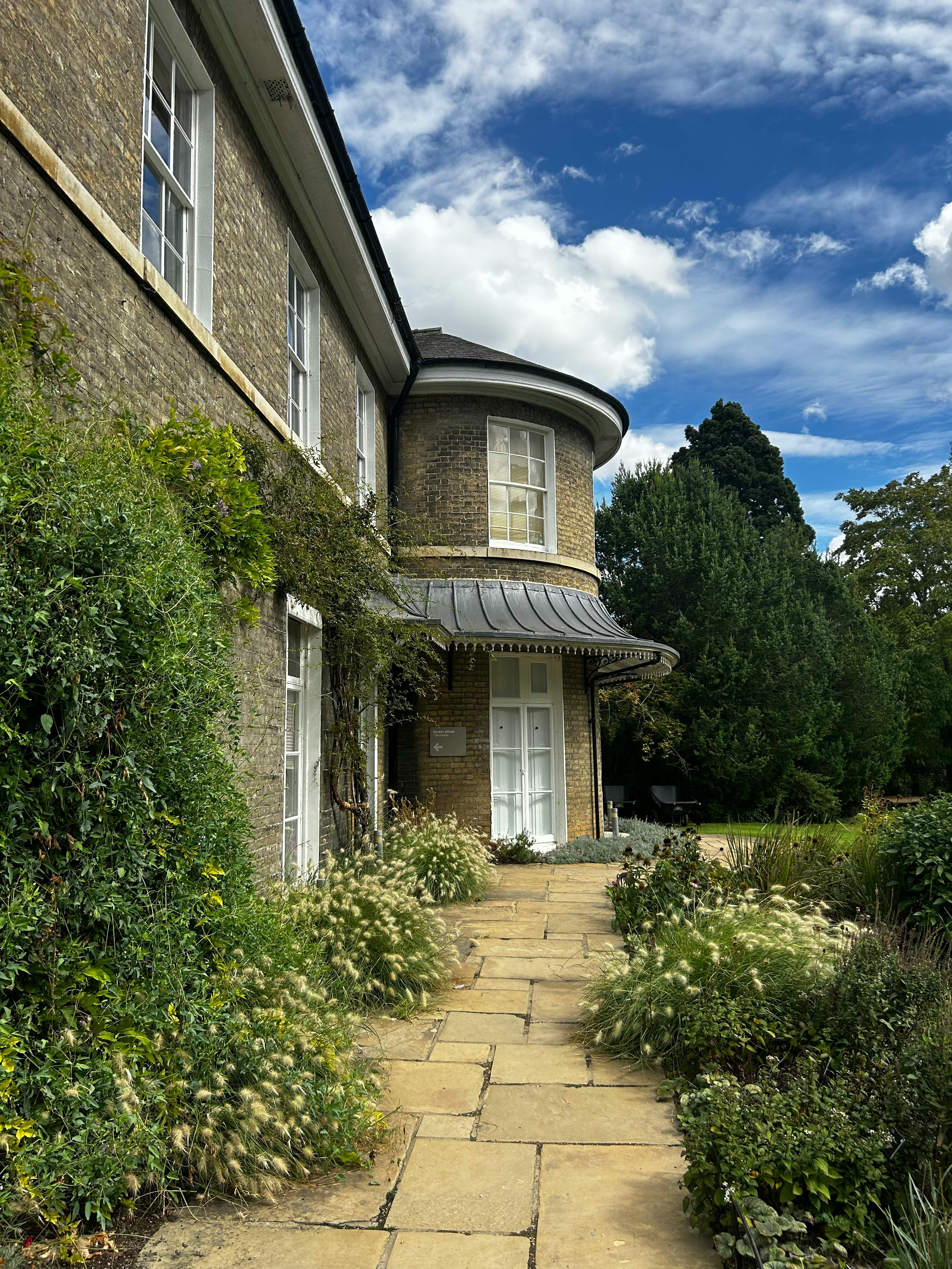 De franc Bonica vista d'una casa històrica a Londres amb una vegetació exuberant i un camí de jardí sota un cel vibrant. Foto d'estoc