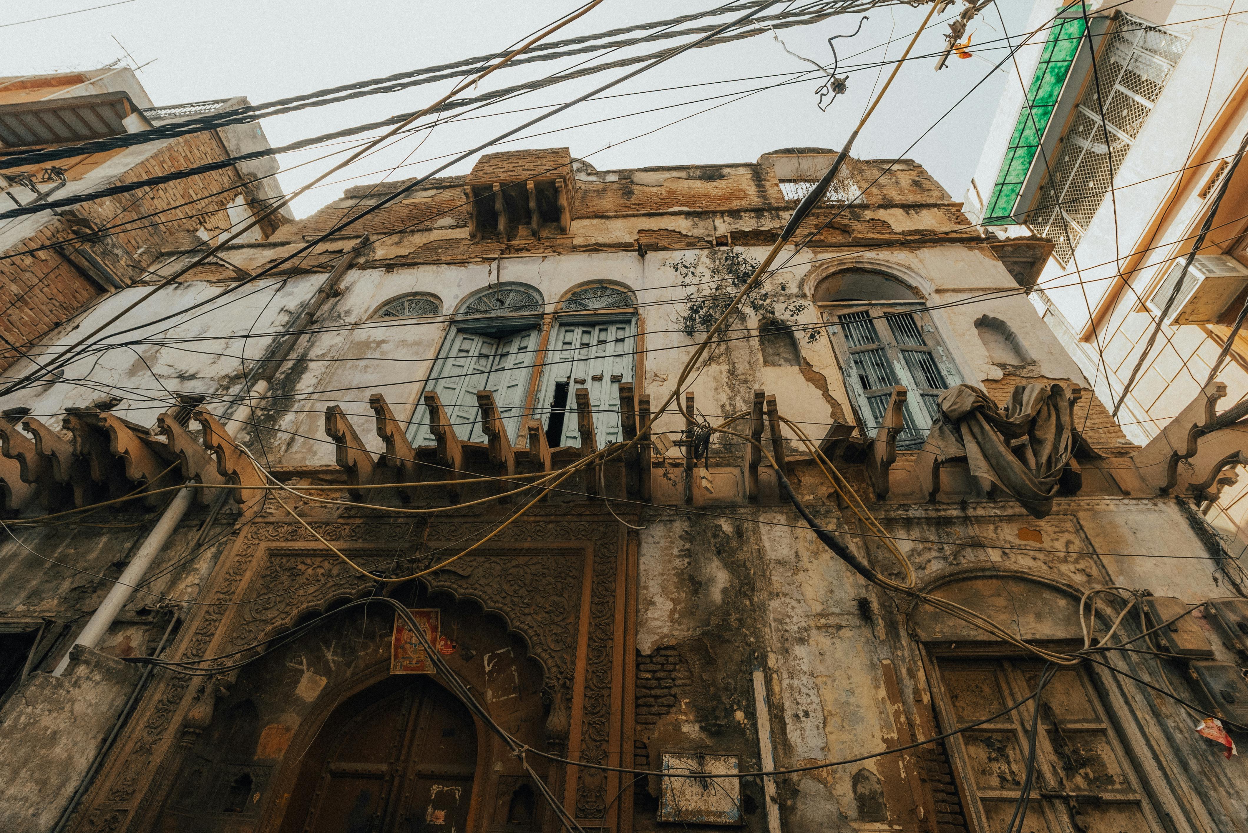 Gratuit Vue détaillée de la façade d'un vieux bâtiment usé par le temps, révélant des détails architecturaux complexes et des câbles apparents. Photos