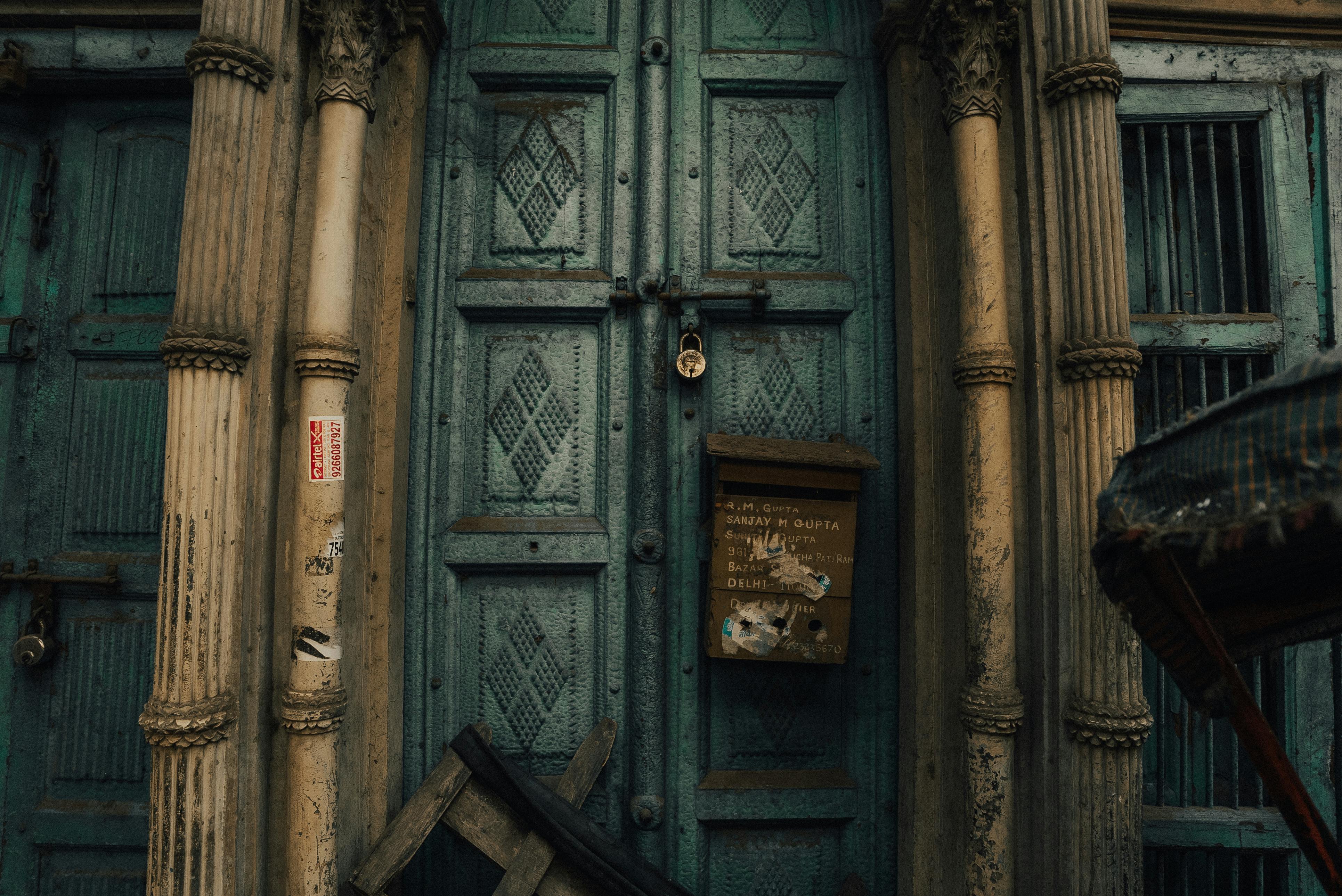 ingyenes Egy Delhiben található, zárt, vintage ajtó részletes oszlopokkal és rusztikus postaládával, amely a városi hanyatlást szimbolizálja. Stockfotó