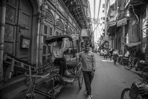 Free A lively street scene in an urban area featuring a rickshaw and local architecture in black and white. Stock Photo