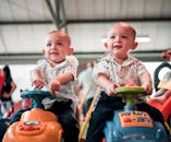 Photo of Two Babies Sitting on Toy Cars