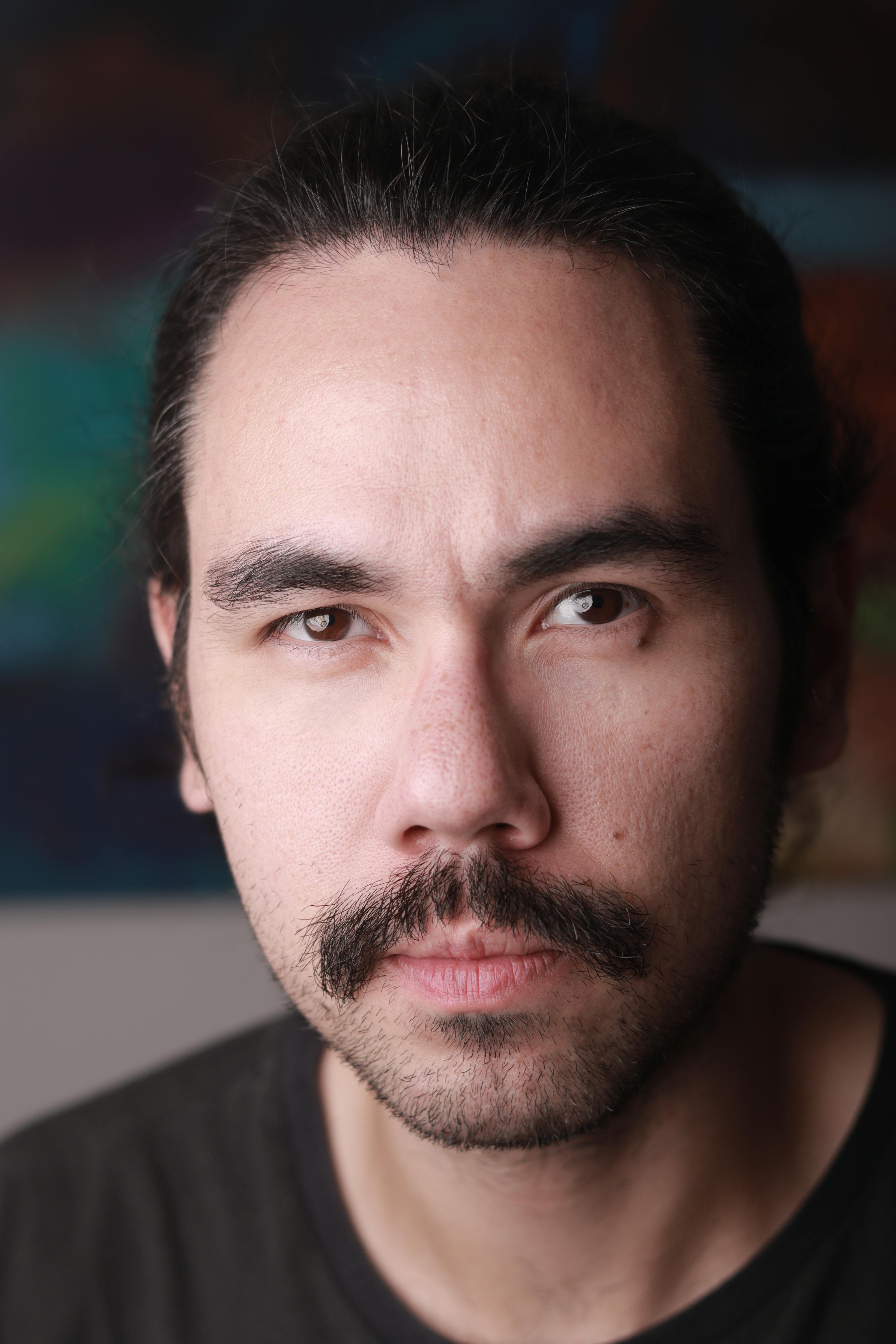 Gratuit Portrait en gros plan d'un homme aux cheveux longs et à la moustache, l'air pensif. Photos