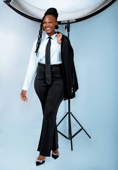 Free Confident woman in a business suit posing with a smile against studio backdrop. Stock Photo