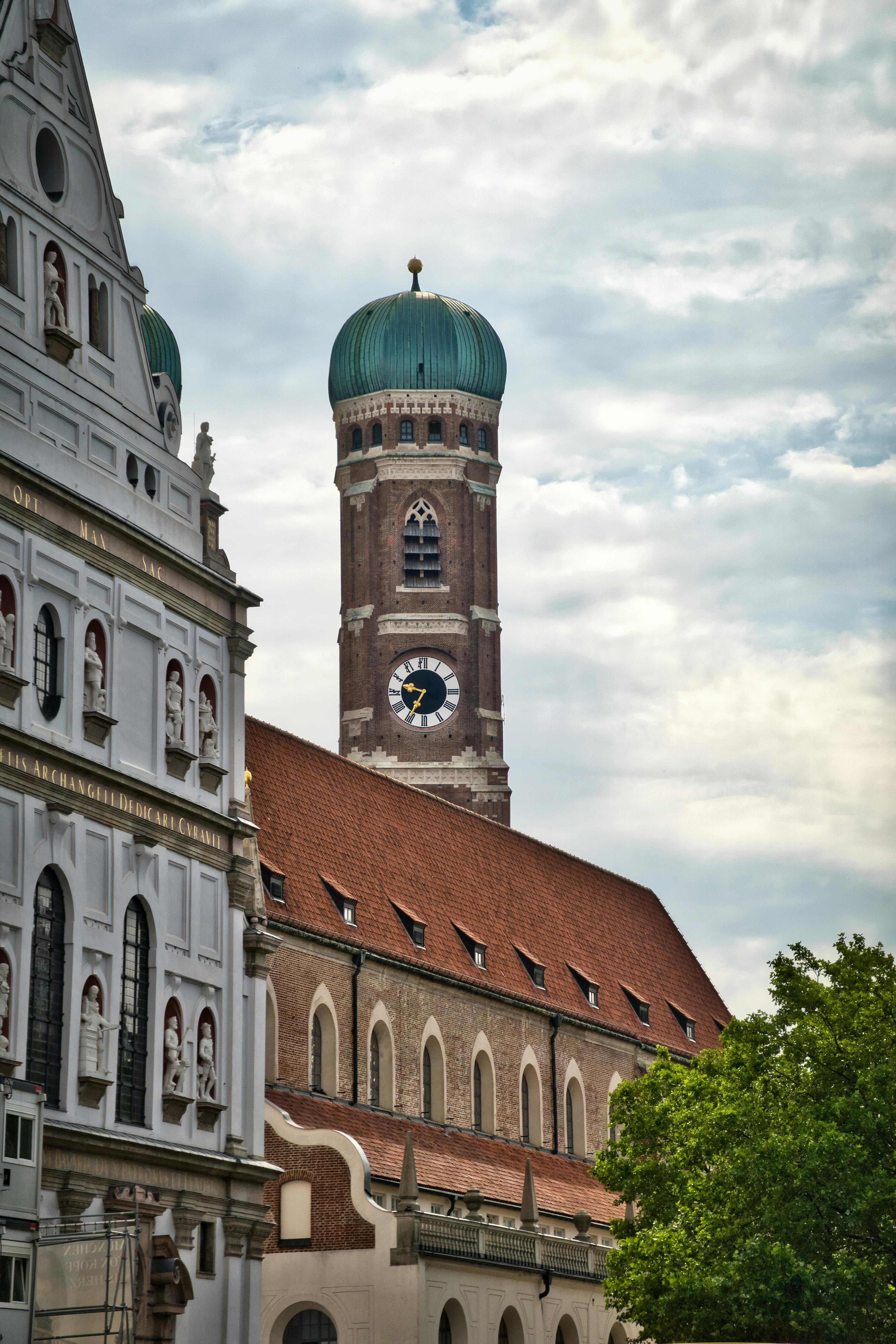 Gratis La storica torre della Frauenkirche di Monaco, che mette in mostra la sua architettura caratteristica sullo sfondo di un cielo nuvoloso. Foto a disposizione
