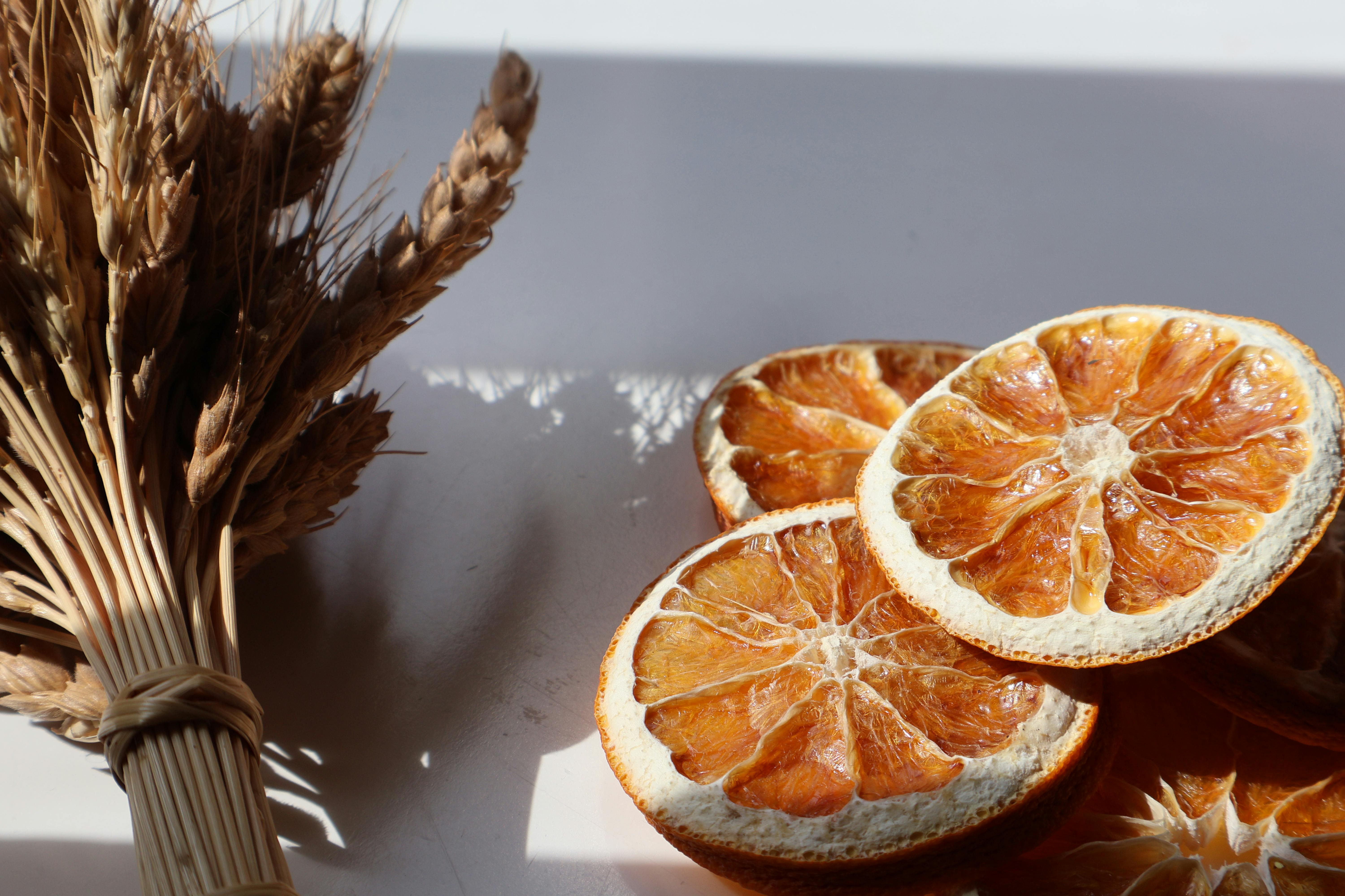 Atmospheric composition of sunlit dried orange slices and wheat bundle casting shadows.