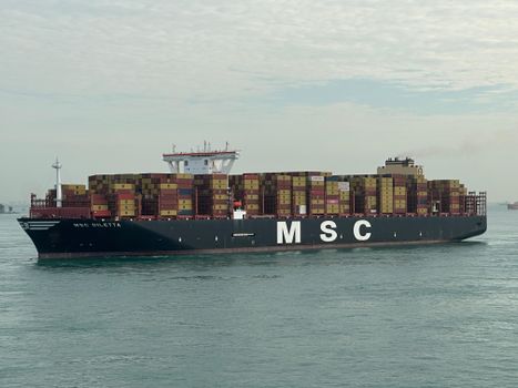 MSC cargo ship with stacked containers navigating open waters under cloudy sky.