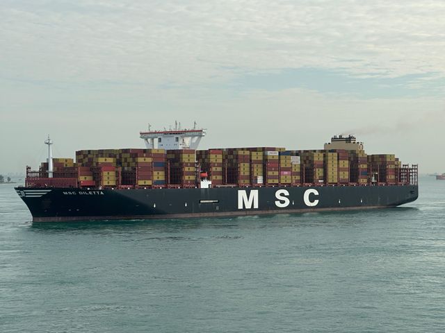 Cargo ship with stacked containers navigating open waters