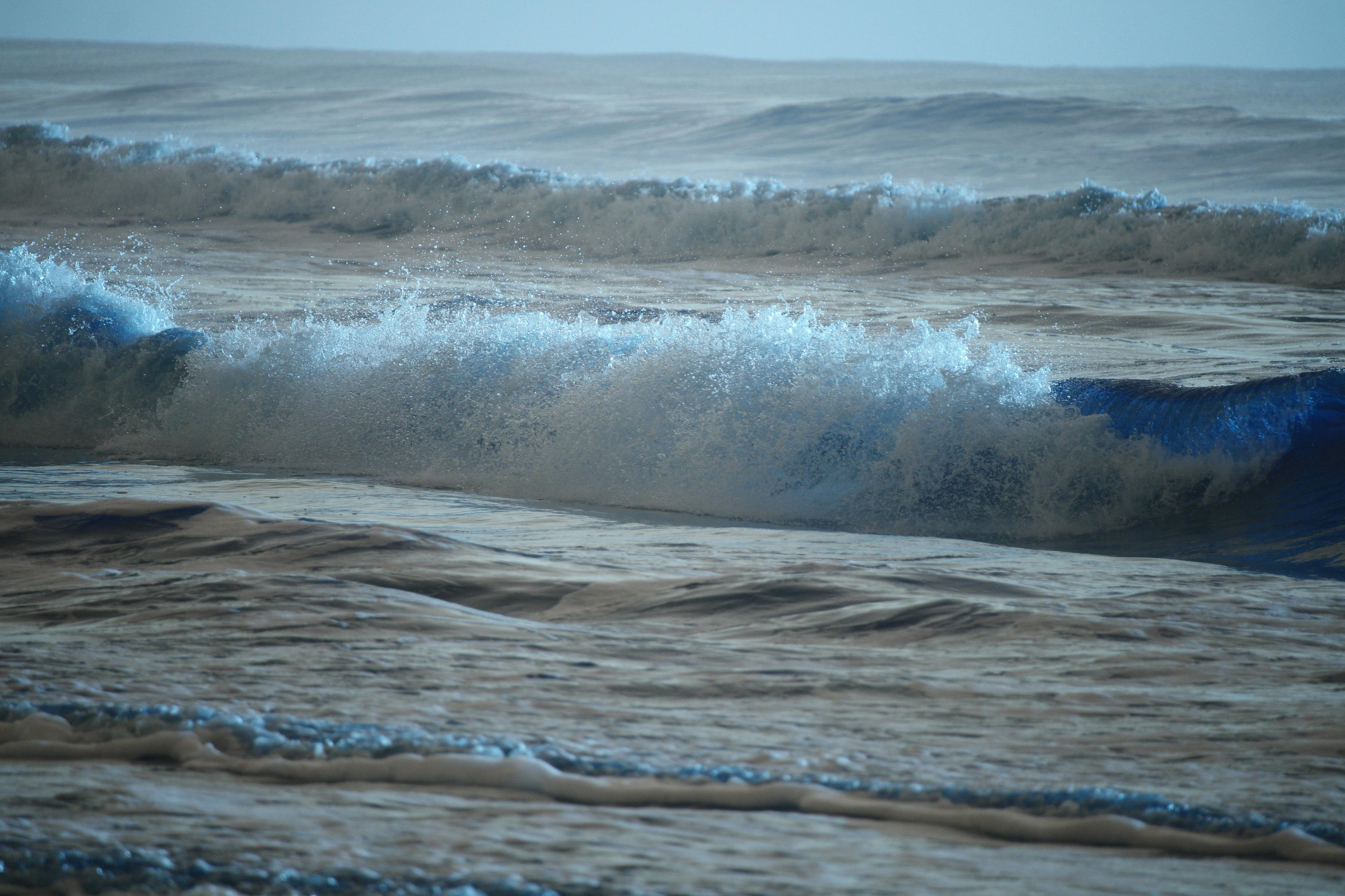 Gratis Immagine di potenti onde oceaniche che si infrangono sulla riva sotto un cielo limpido. Foto a disposizione