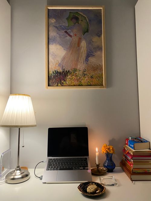 Free A cozy home office setup with a laptop, books, and art decor creating an inviting workspace ambiance. Stock Photo