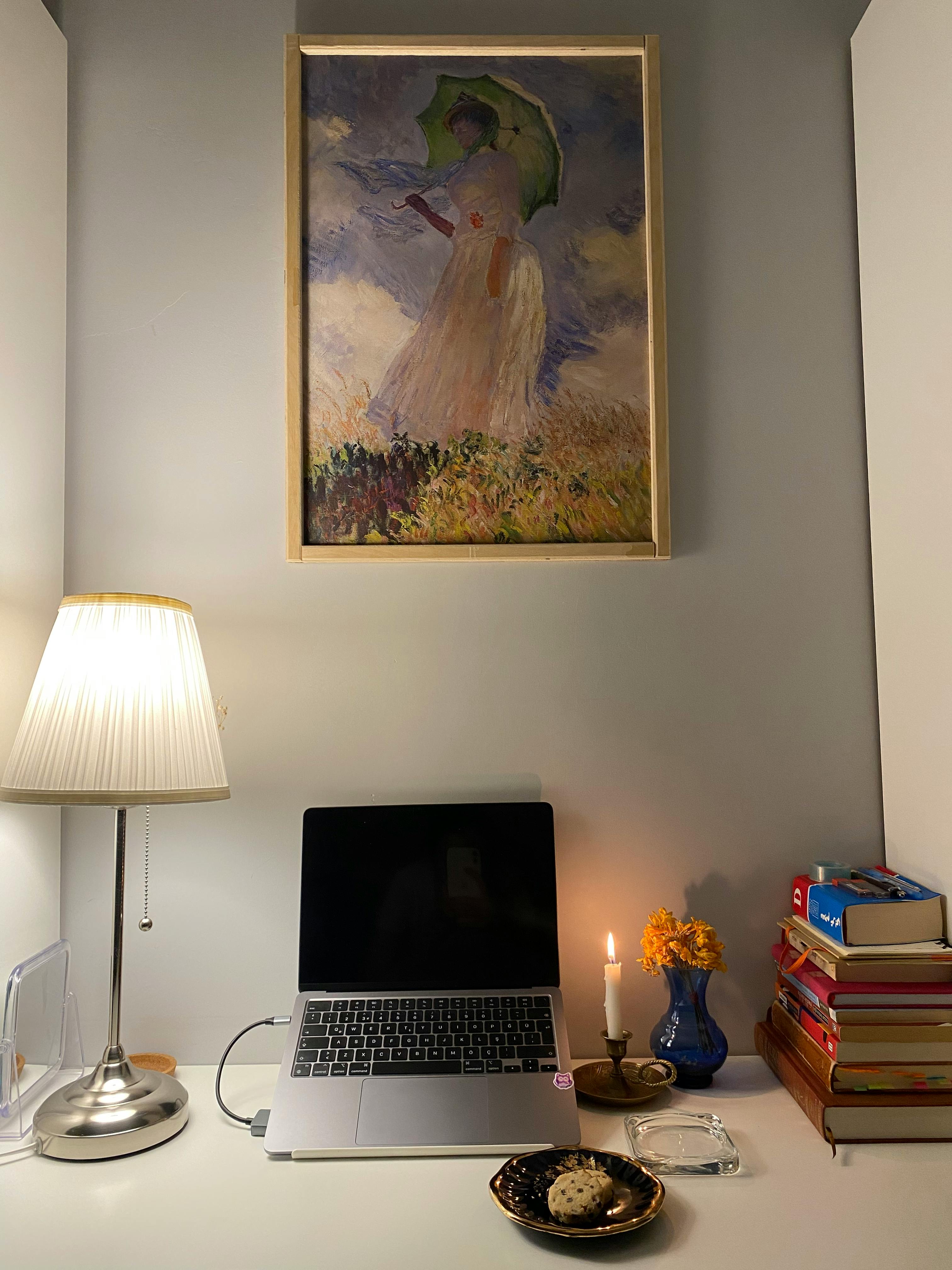 Kostenlos Ein gemütliches Homeoffice mit Laptop, Büchern und Kunstdekoration schafft eine einladende Arbeitsatmosphäre. Stock-Foto