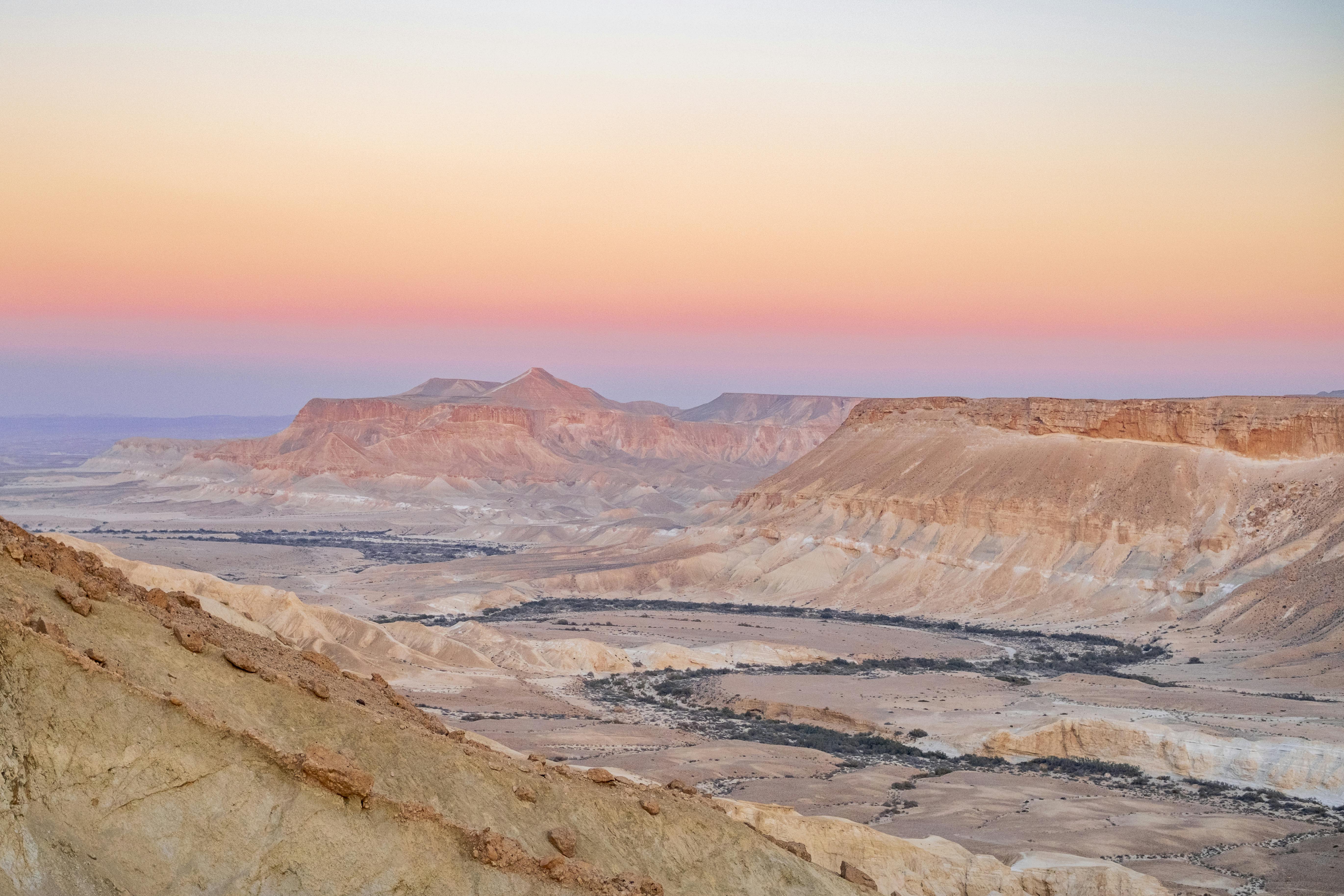 bezplatná Úchvatný výhled na Negevskou poušť při západu slunce s barevnou oblohou nad drsnými kaňony v jižním Izraeli. Základová fotografie